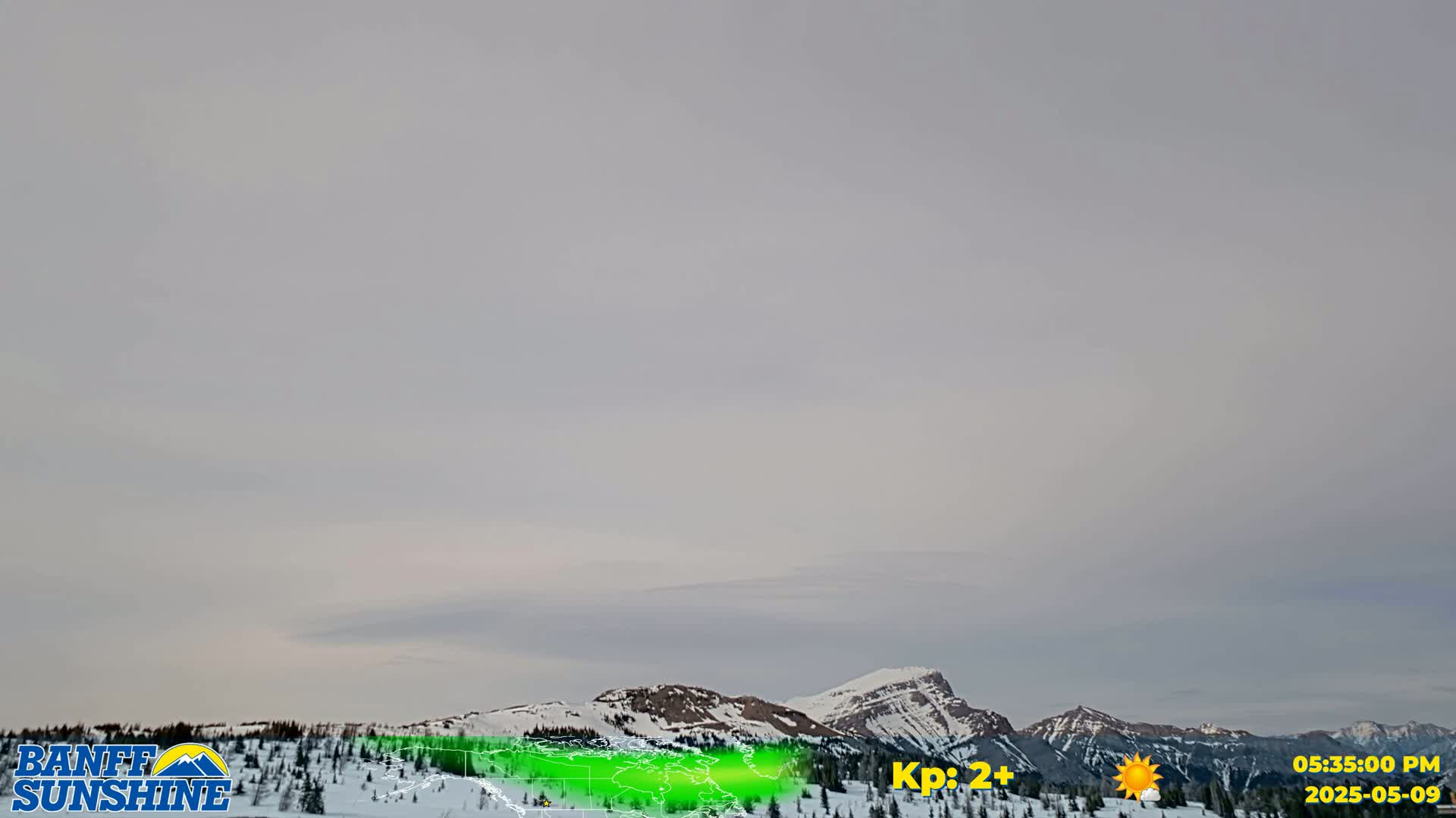 Under a mostly cloudy sky, snow-covered mountains are visible in the distance.