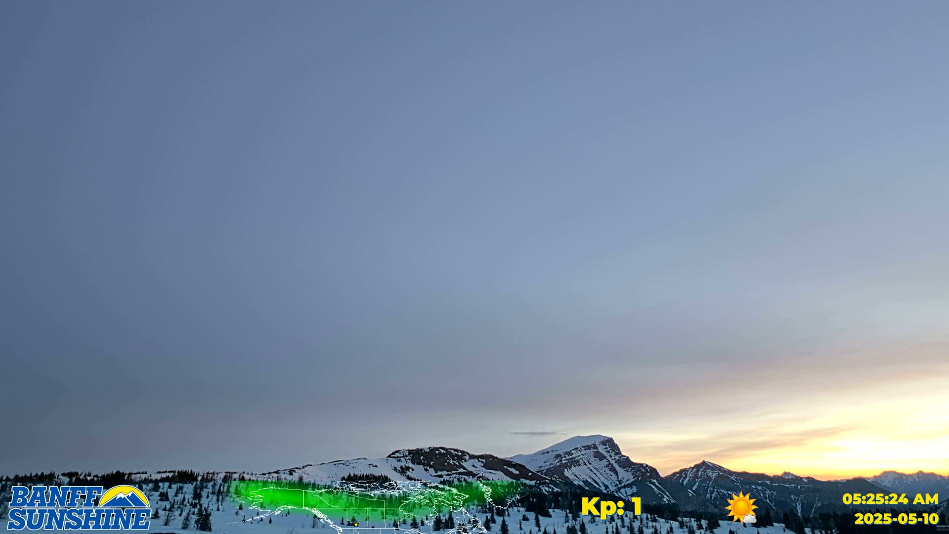 A snow-covered mountain range is visible at sunrise under a clear, pale blue sky.