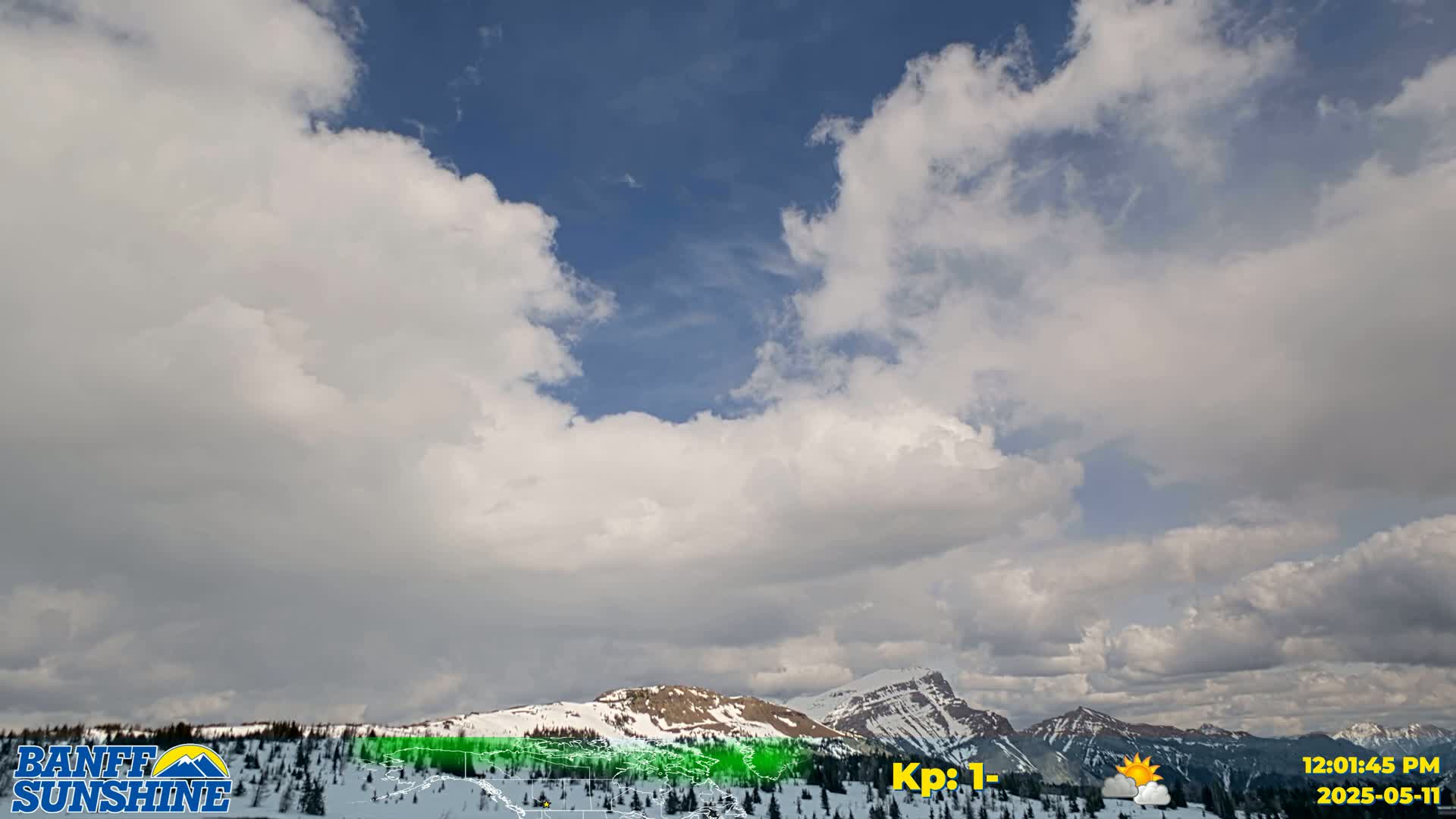 A partly cloudy sky over snow-capped mountains.