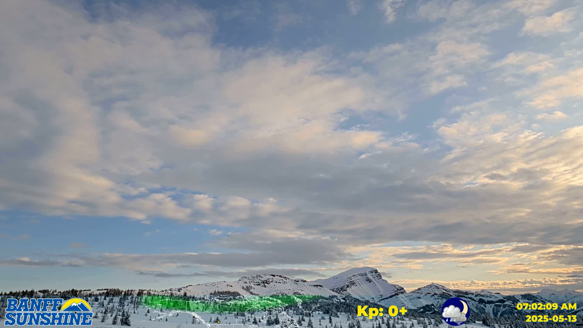A partly cloudy sky over snow-covered mountains.