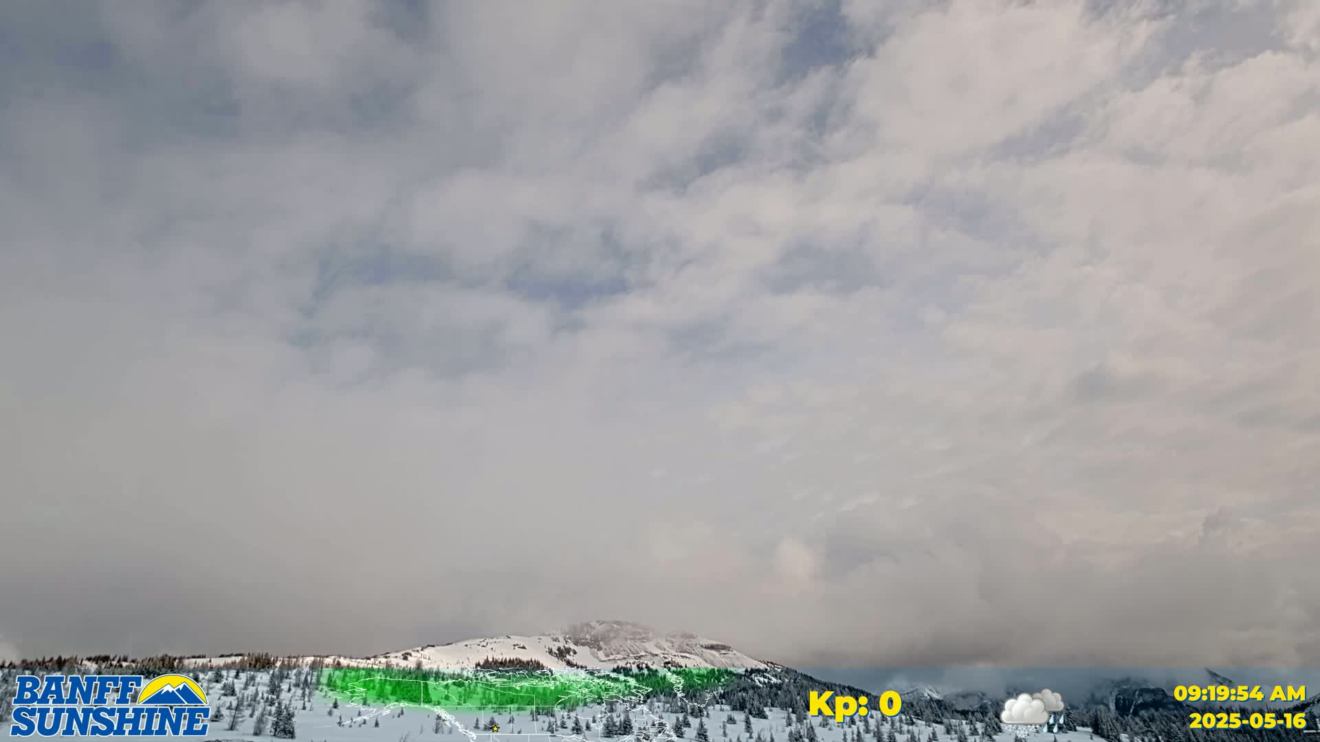 A snow-covered mountain range is visible under a mostly cloudy sky.