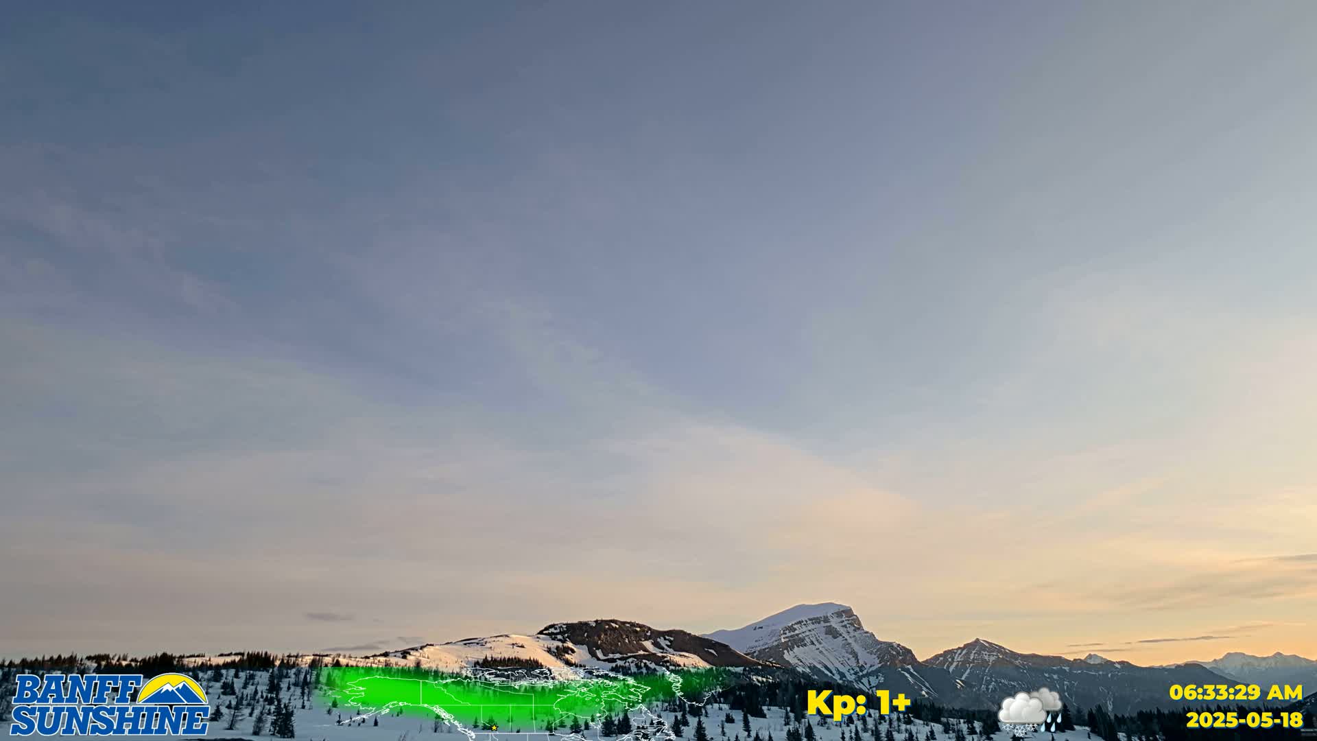 A snow-covered mountain range is visible at sunrise under a mostly clear, pale blue sky with wispy clouds.