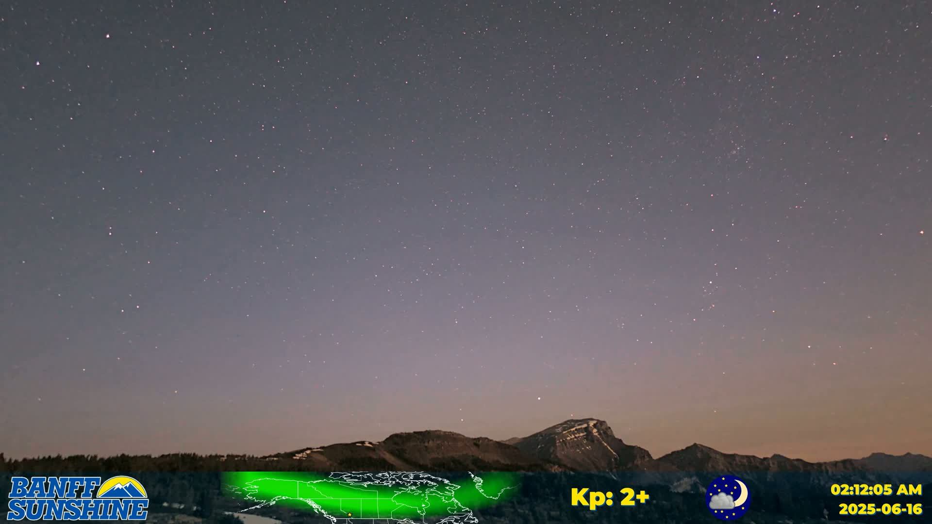 A clear night sky filled with stars is over a mountain range.