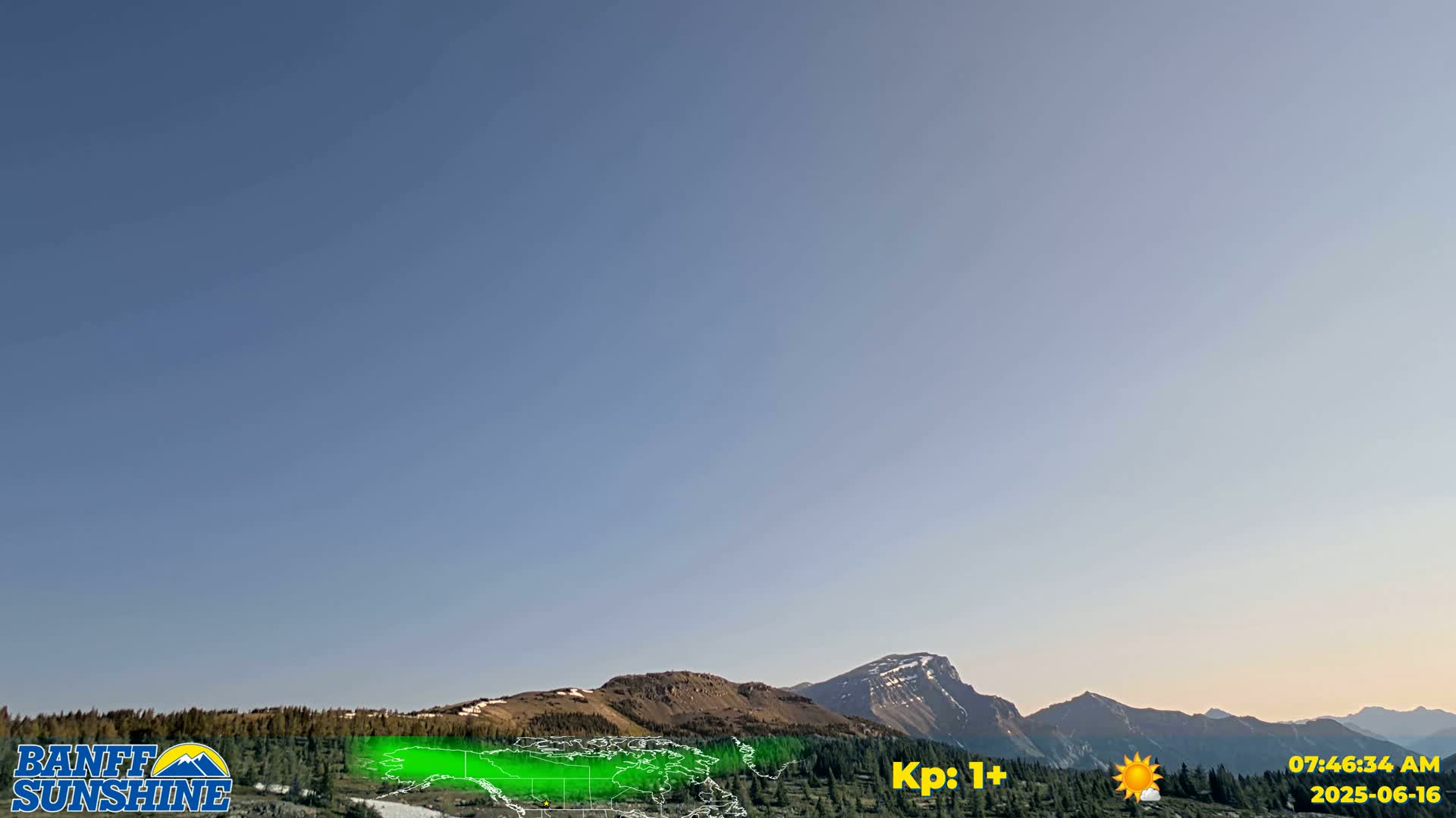 A clear, sunny sky overlooks a range of mountains with some snow visible on the peaks.