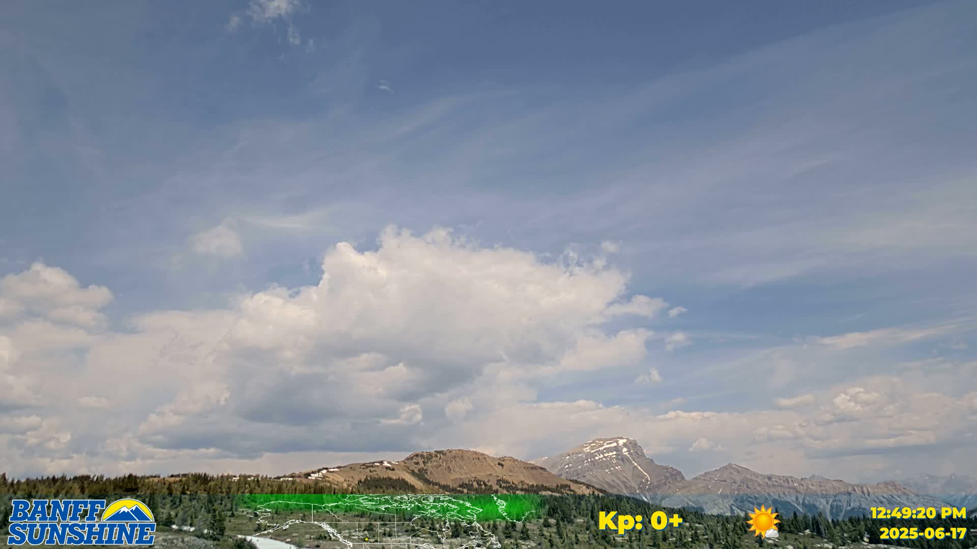 A partly cloudy sky over a mountain range with some snow on the peaks.