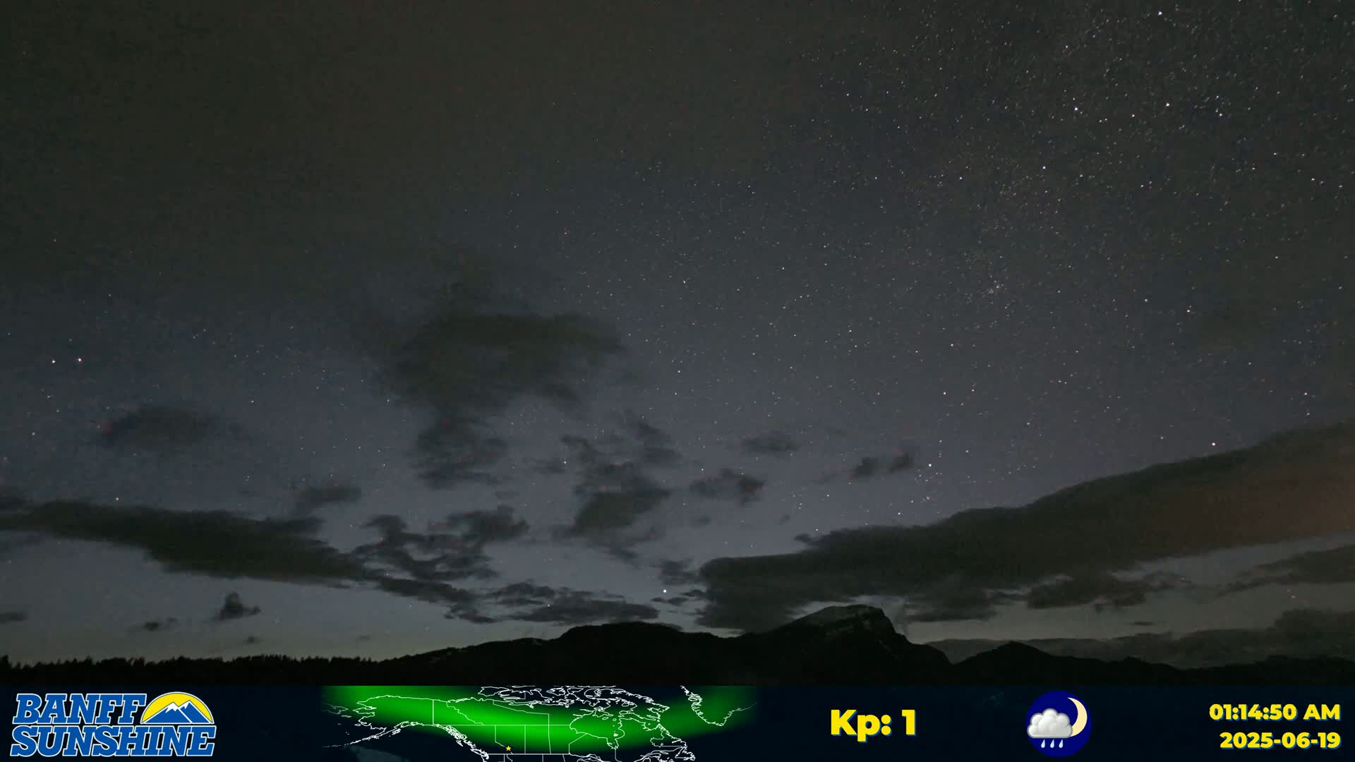 A night sky filled with stars and some clouds above a dark mountain range, with light rain.