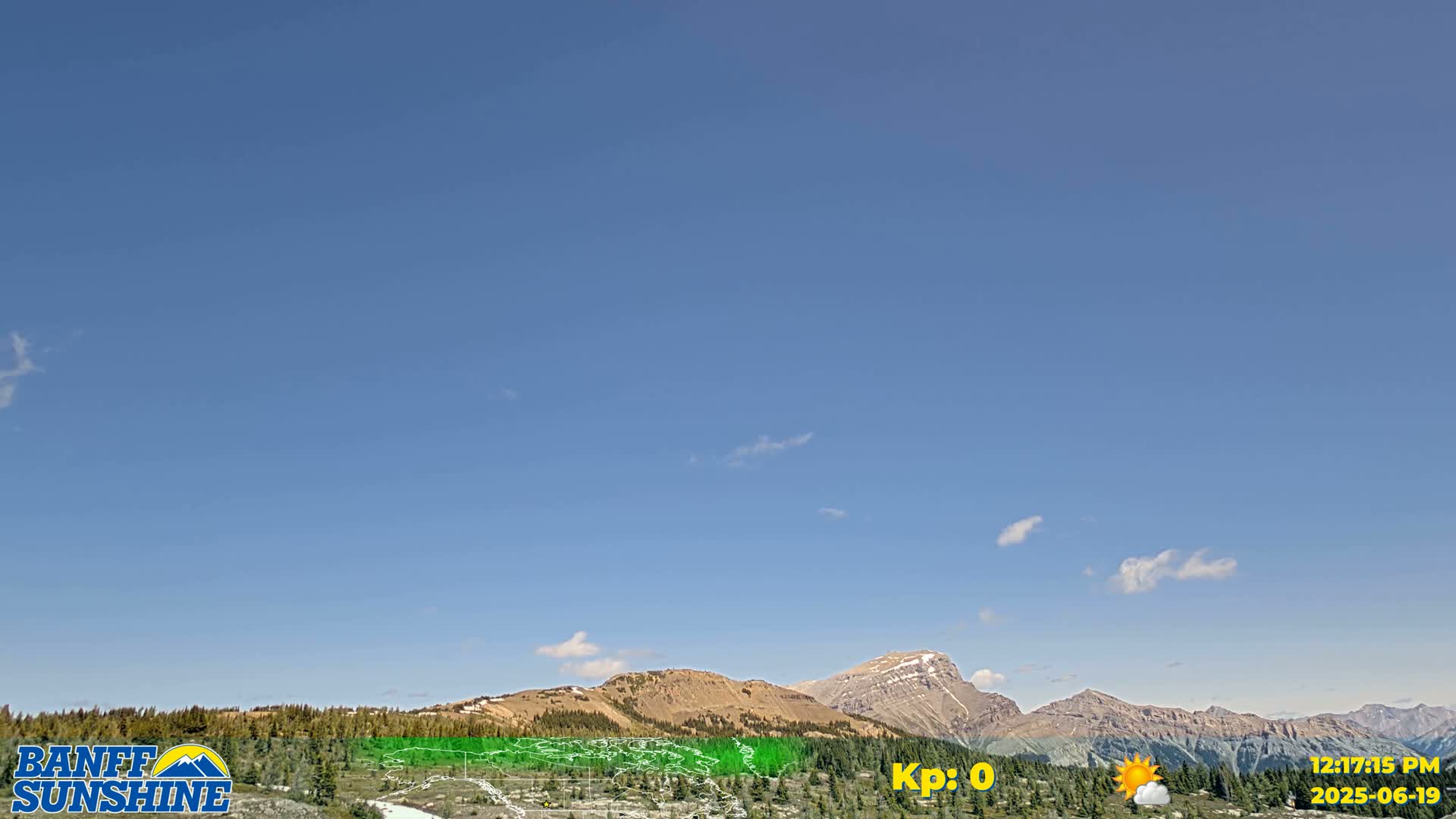 A mostly clear blue sky overlooks a mountain range with sparse, low clouds.