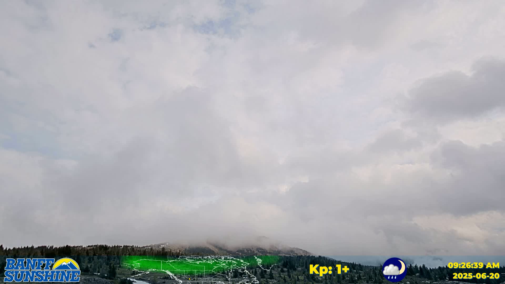 A mostly cloudy, overcast sky hangs over a low-lying mountain range partially obscured by fog or mist.