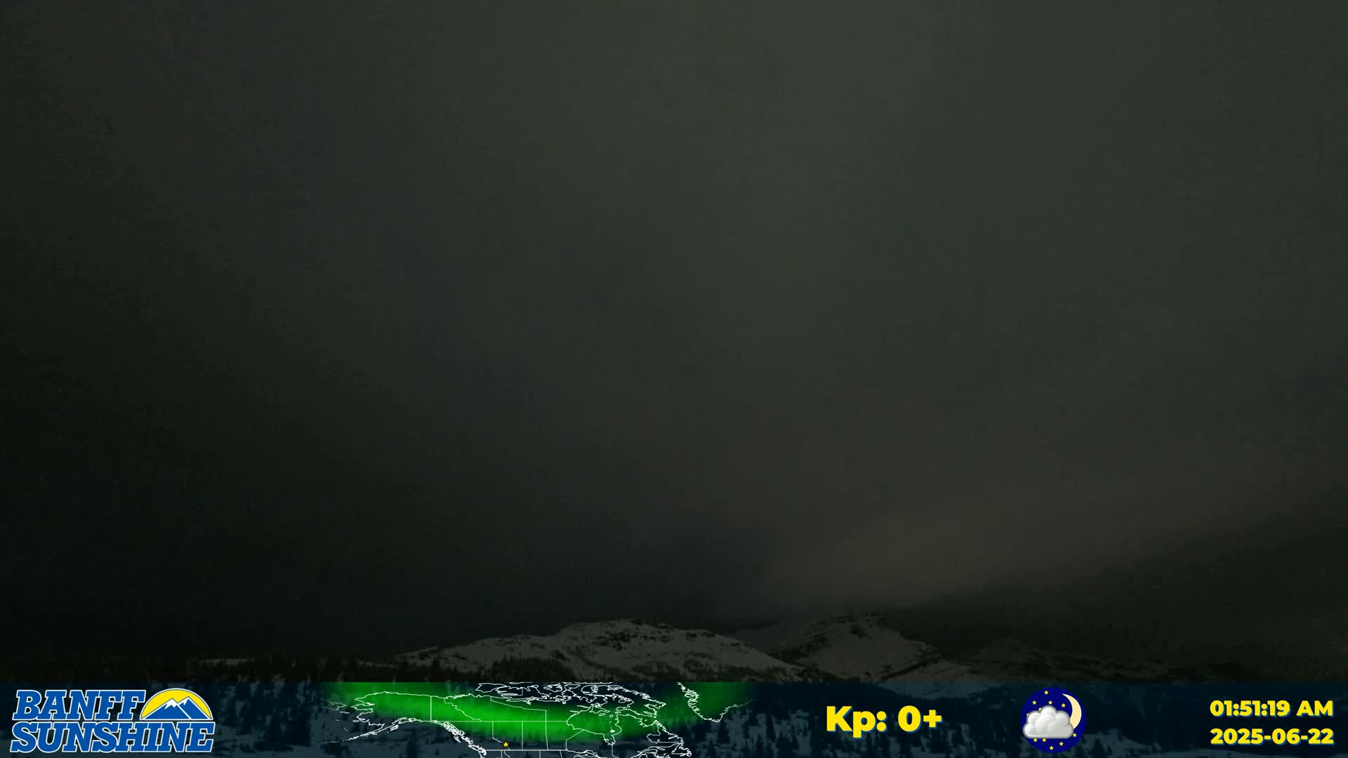 A dark, overcast sky hangs over snow-covered mountains at night.
