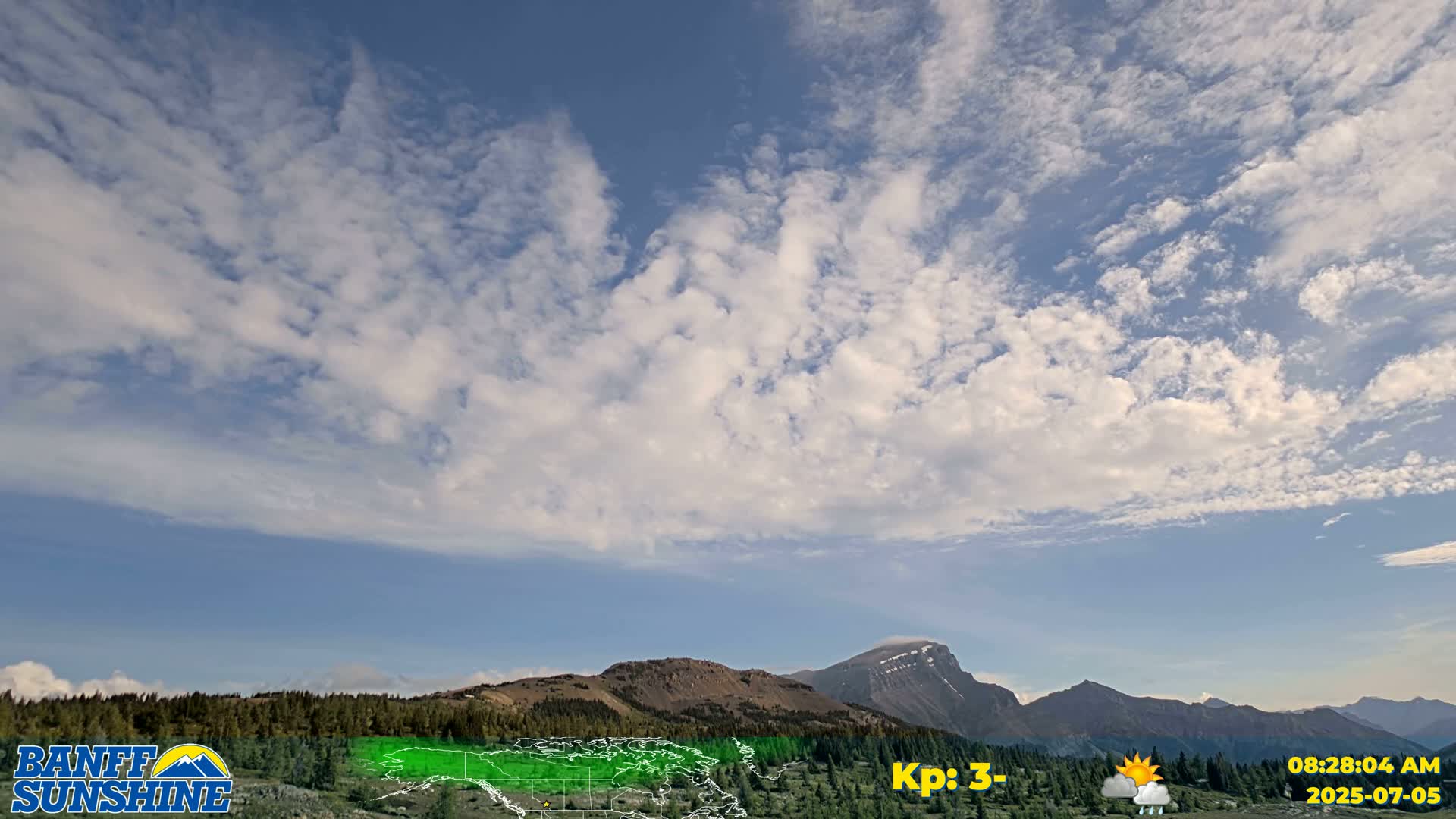 A mostly sunny sky with scattered clouds over a mountainous landscape.