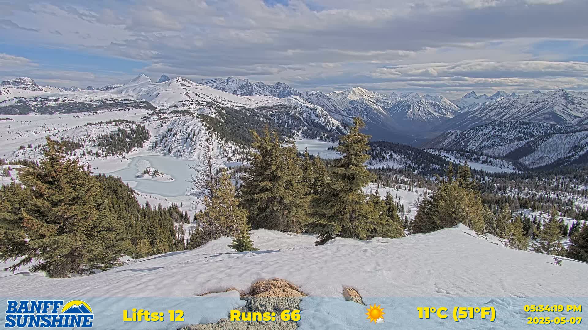 A snow-covered mountain vista with a partly frozen lake is visible under a partly cloudy sky.