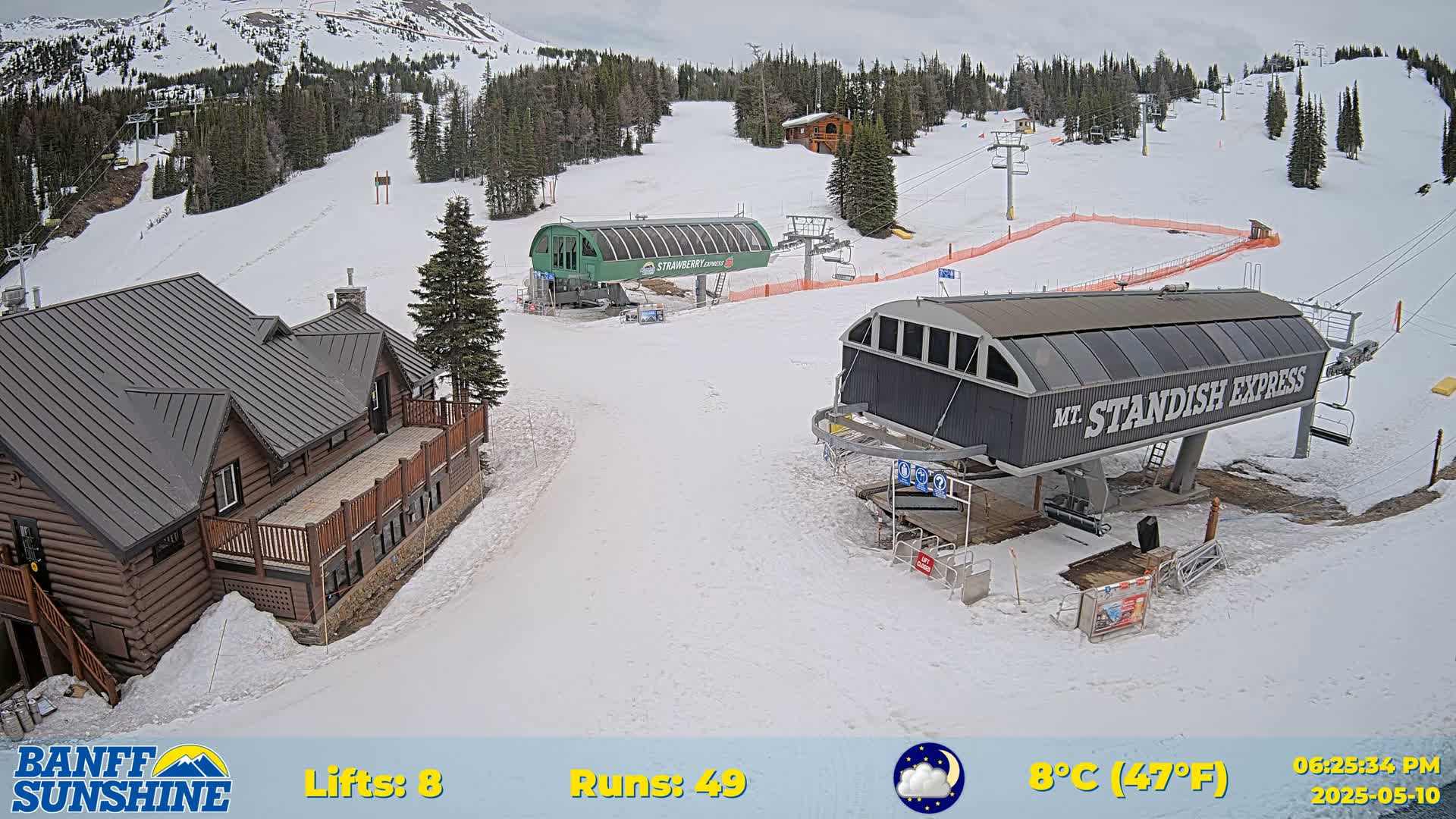 A ski resort with two chairlifts, a log cabin, and snow-covered slopes under a cloudy sky.