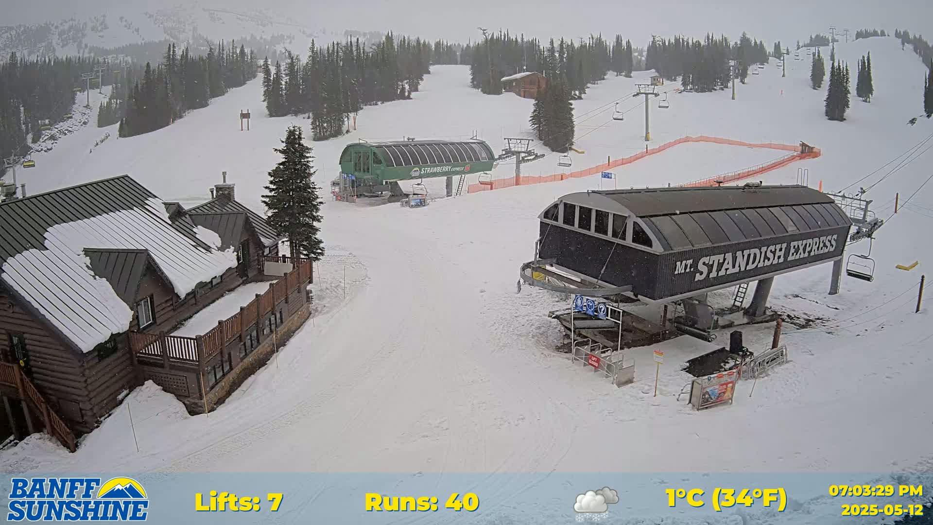 A snow-covered ski resort with two chairlifts and a lodge, under overcast skies with light snow falling.