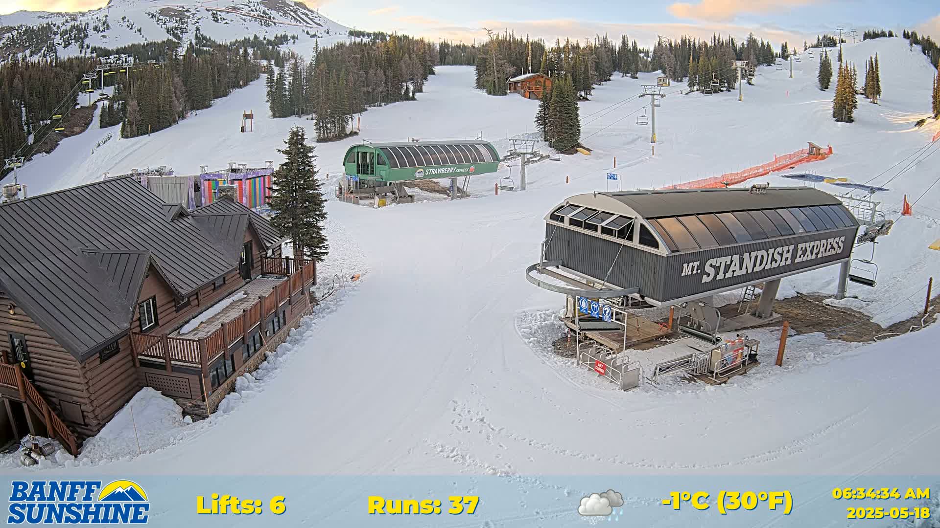 A snow-covered ski resort with several ski lifts and a lodge, under lightly cloudy skies and a temperature of -1°C (30°F).