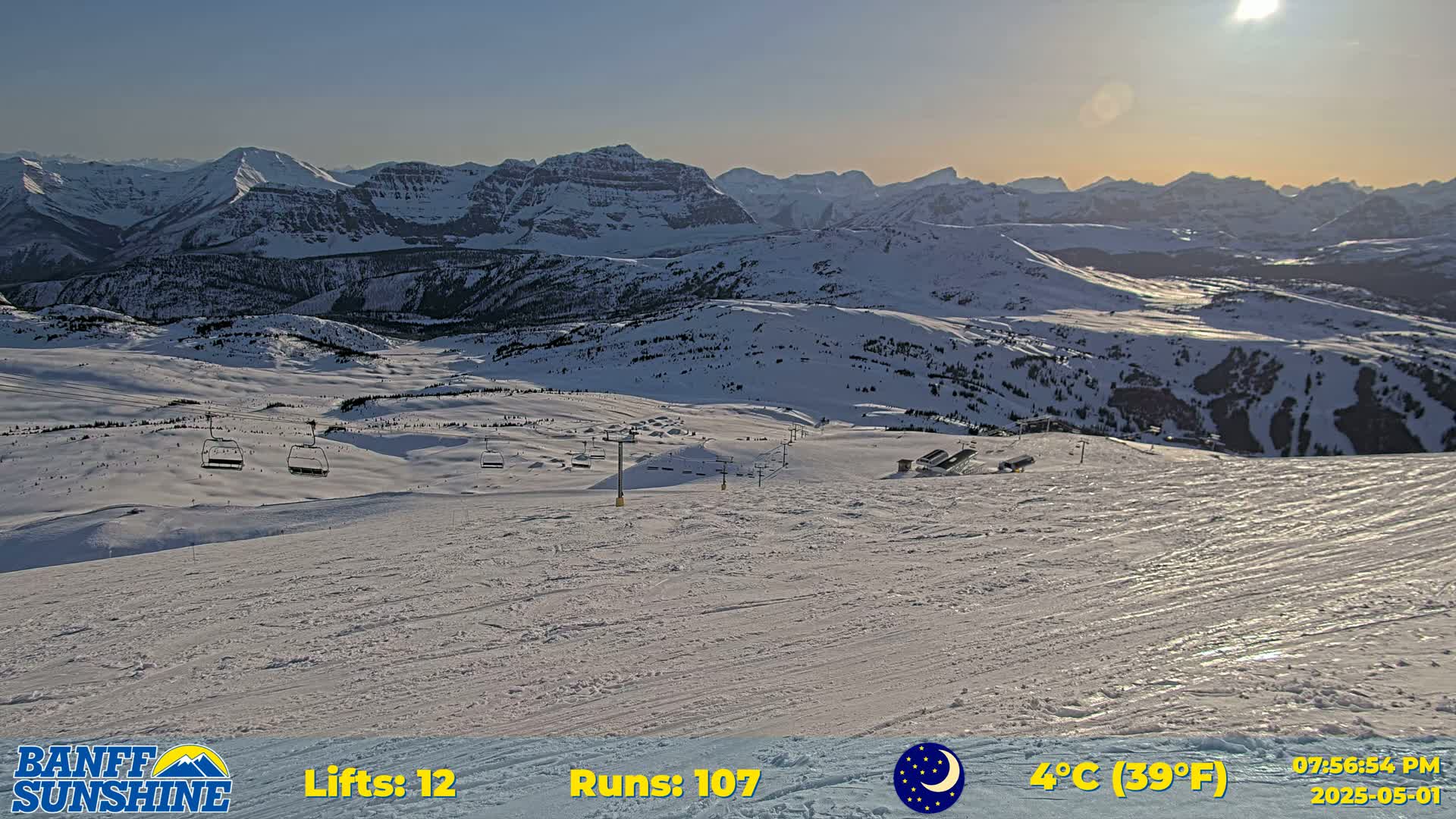 A sunny, snow-covered mountain landscape with ski lifts and runs visible in the distance.