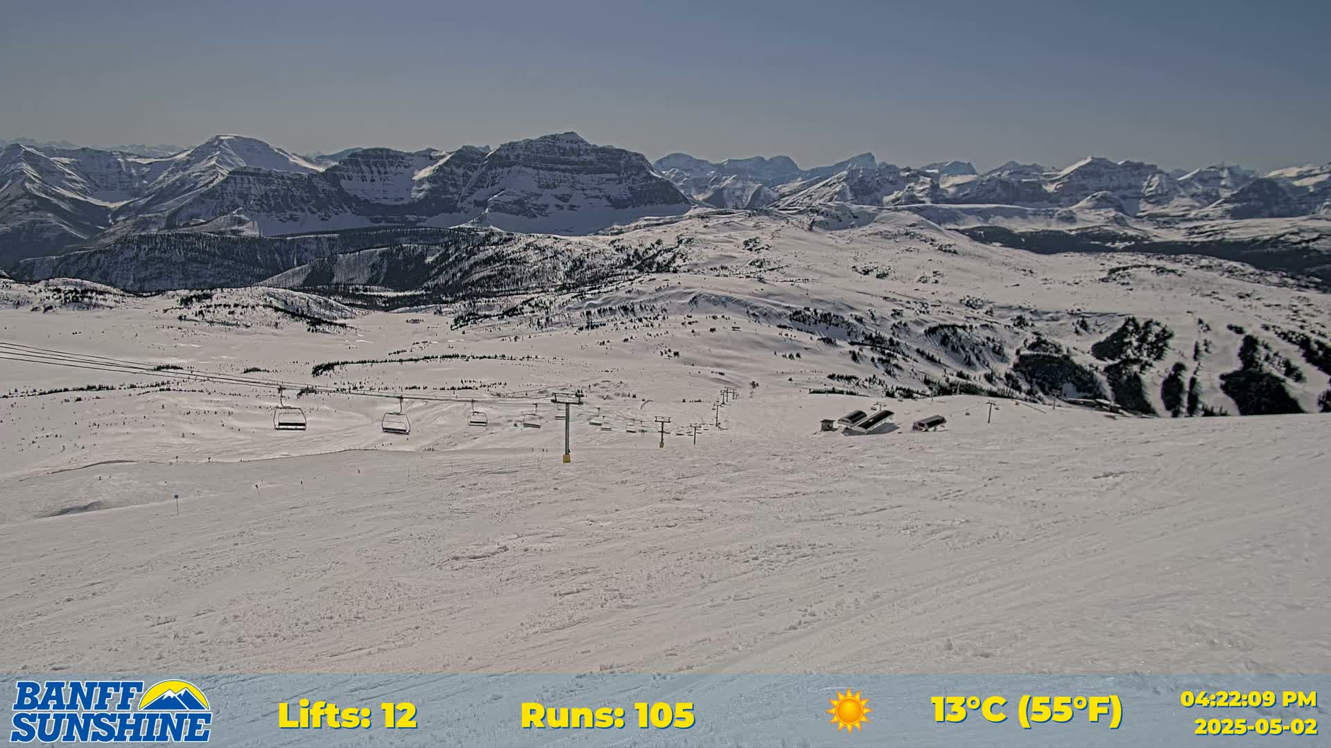 A sunny, snow-covered ski resort with chairlifts and mountain views in the background.