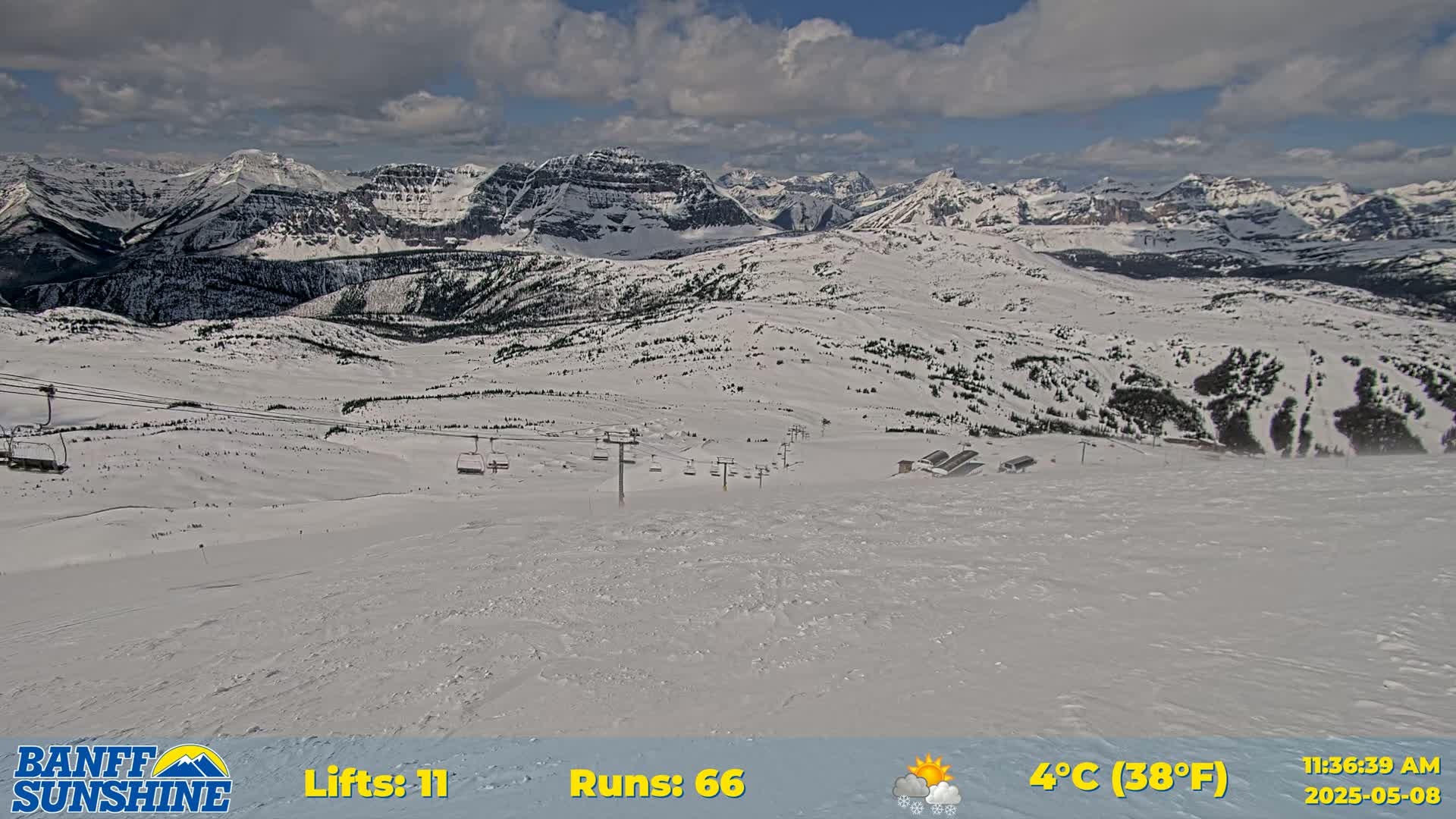 A snowy mountain landscape with ski lifts and runs visible under partly cloudy skies.
