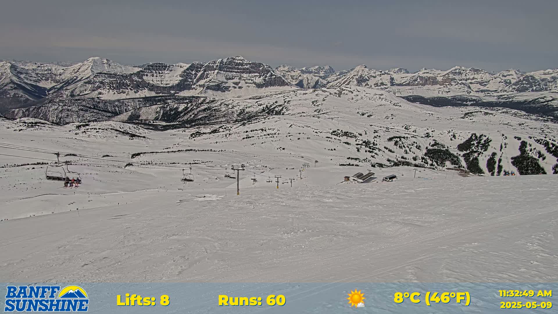 A snowy mountain landscape with ski lifts and runs under a partly sunny sky.