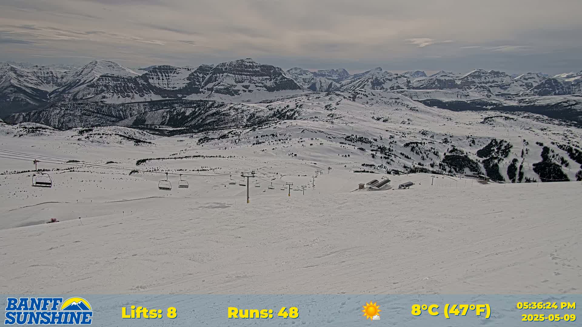 A snowy ski resort with chairlifts and several runs is visible against a backdrop of overcast mountains.