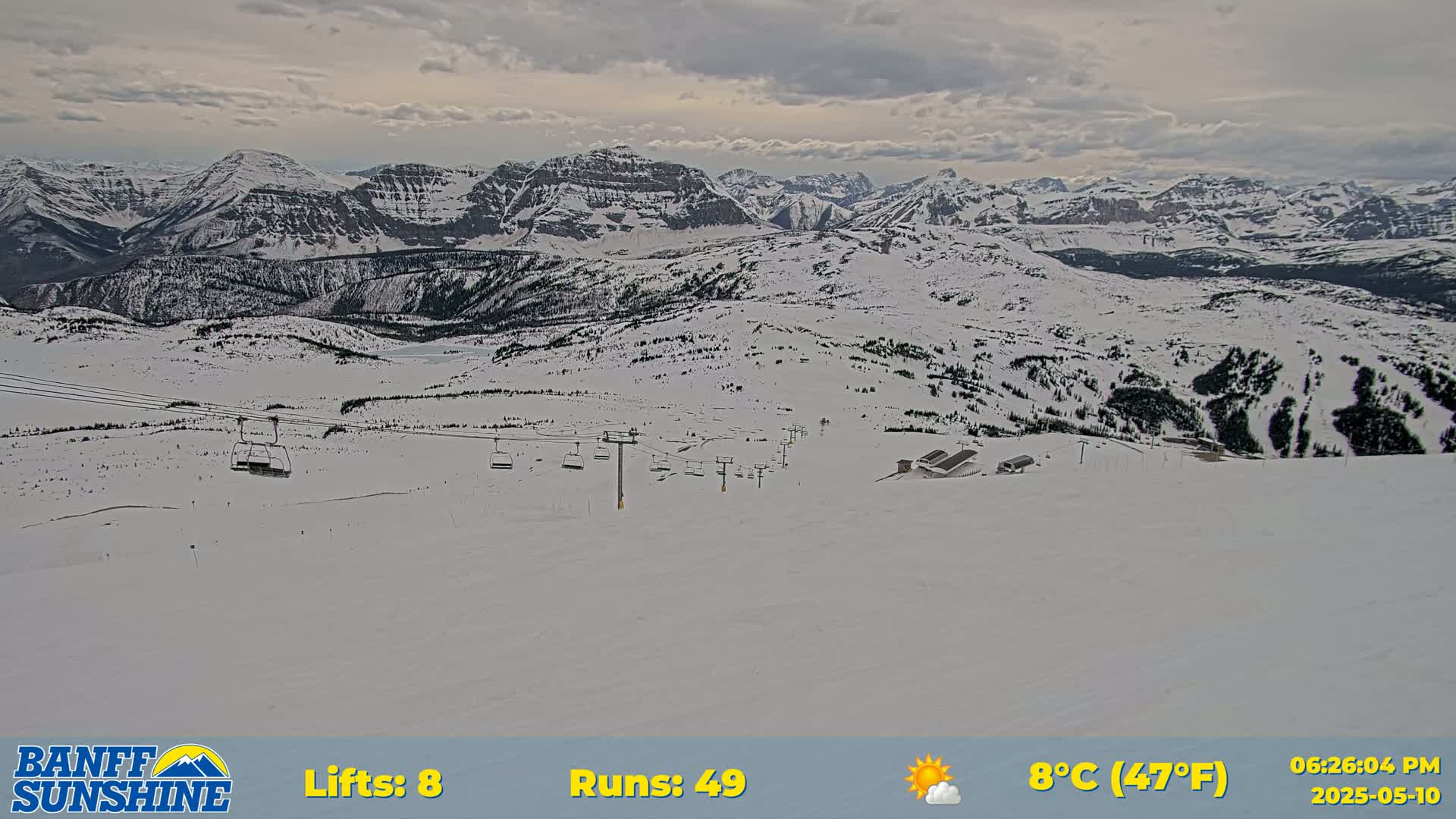 A snowy mountain ski resort with several chairlifts visible under a partly cloudy sky.