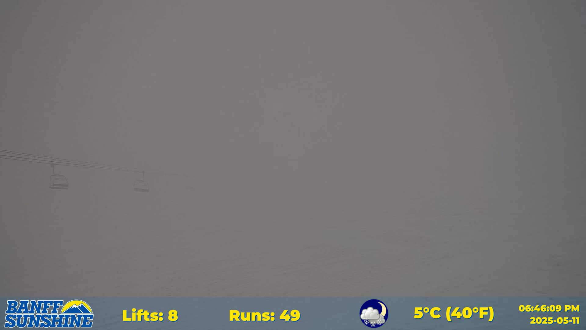 A foggy view shows a chairlift carrying two empty gondolas.