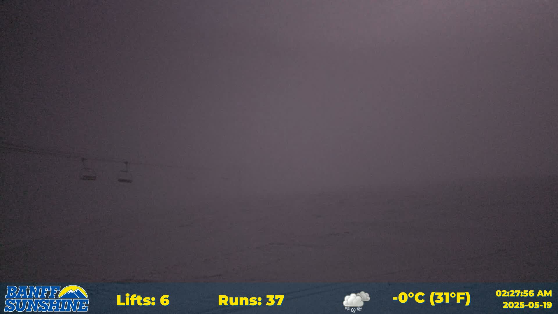 A snowy, foggy landscape is visible with two chairlifts in the distance.