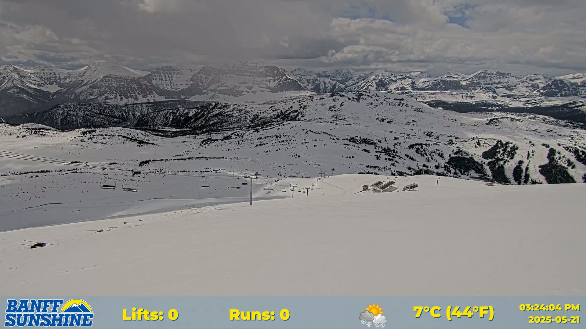 A snow-covered mountain landscape with ski lifts under partly cloudy skies.