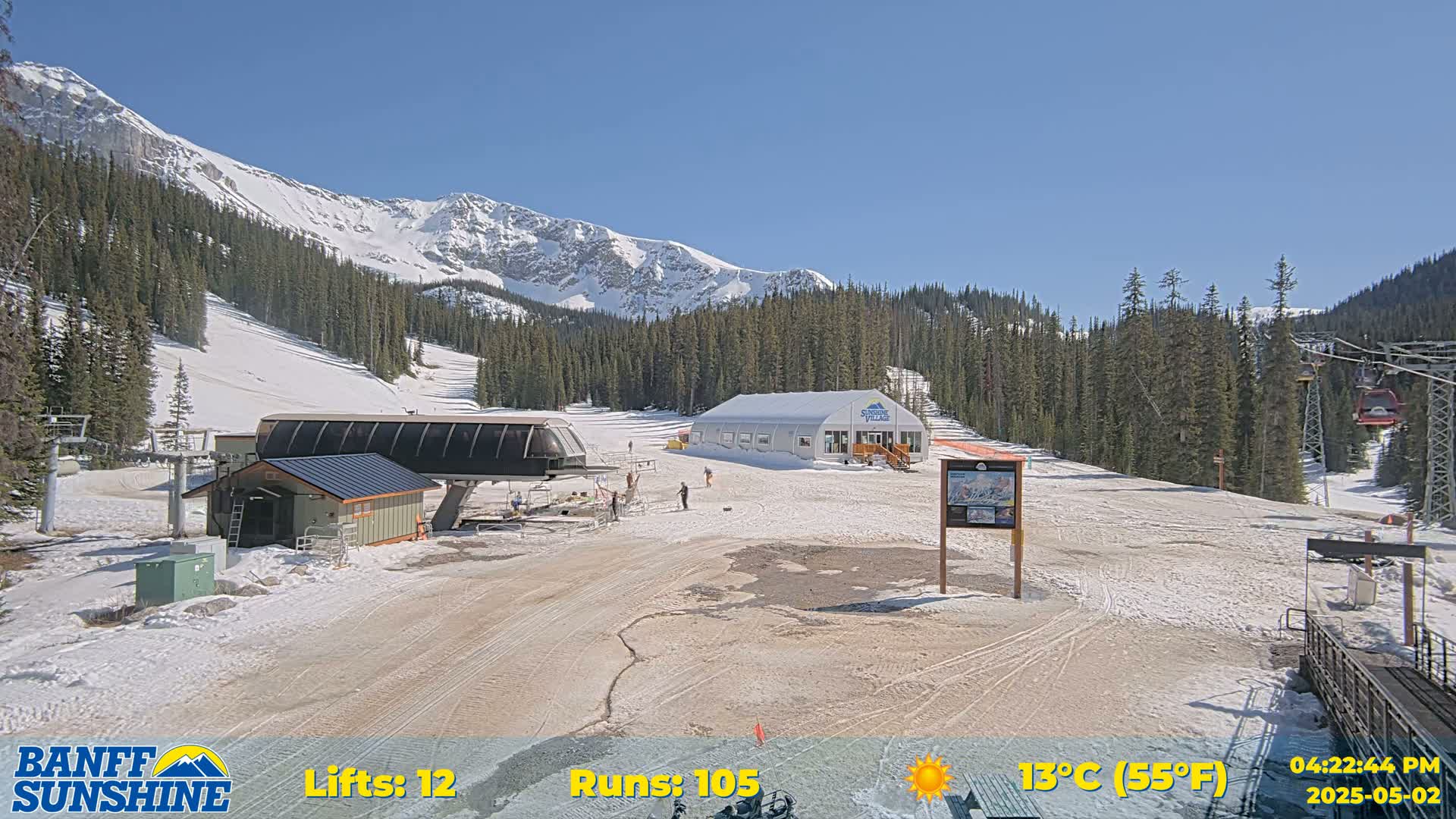A sunny ski resort scene shows a chairlift, a lodge, and several people on a snowy mountainside.
