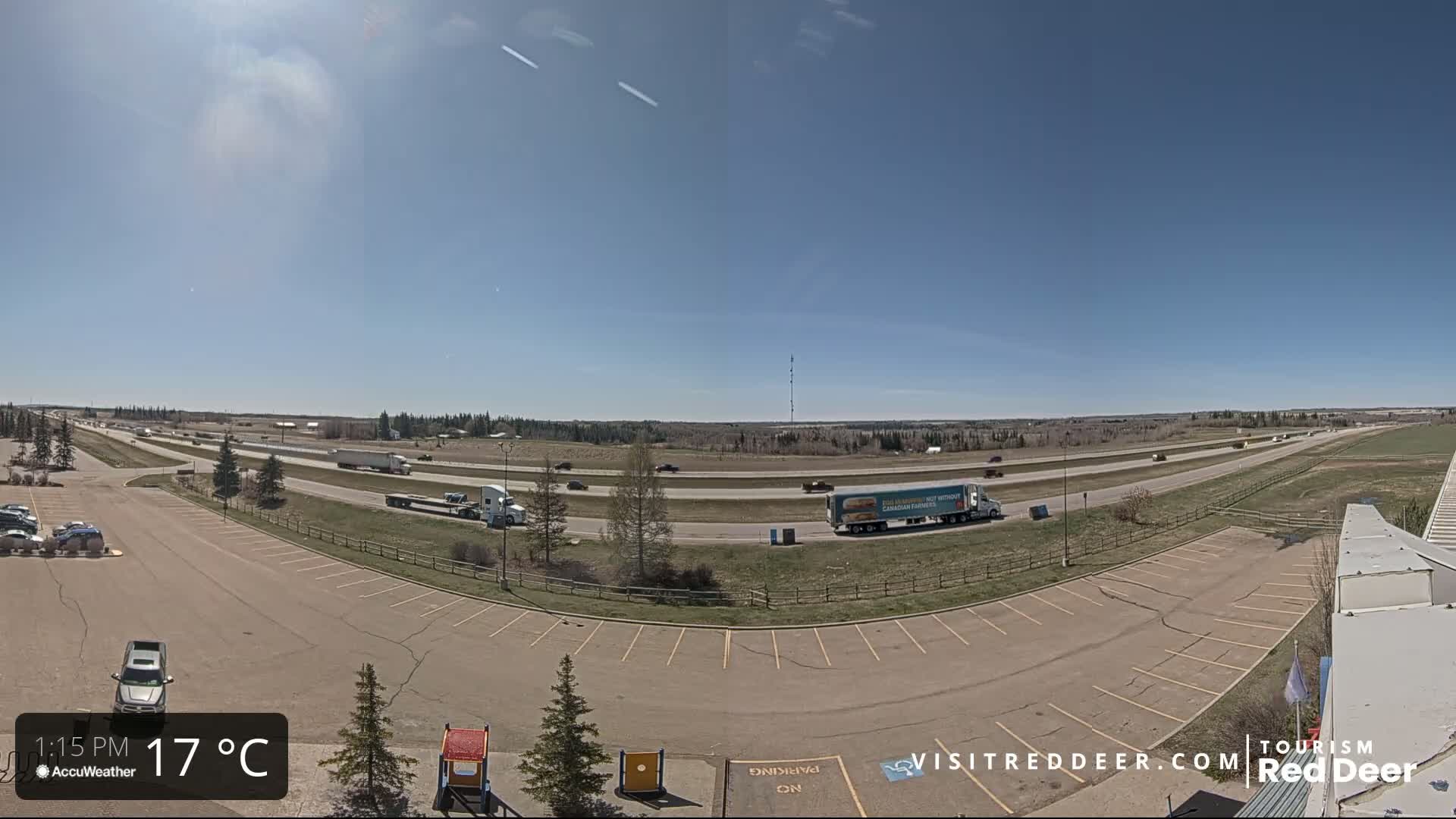 A highway with moderate traffic is visible from a parking lot on a sunny 17°C day.