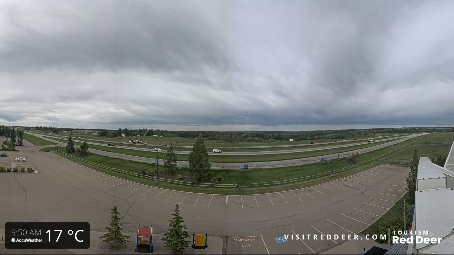 A mostly cloudy, 17°C day shows a highway with light traffic and an empty parking lot next to a grassy area.