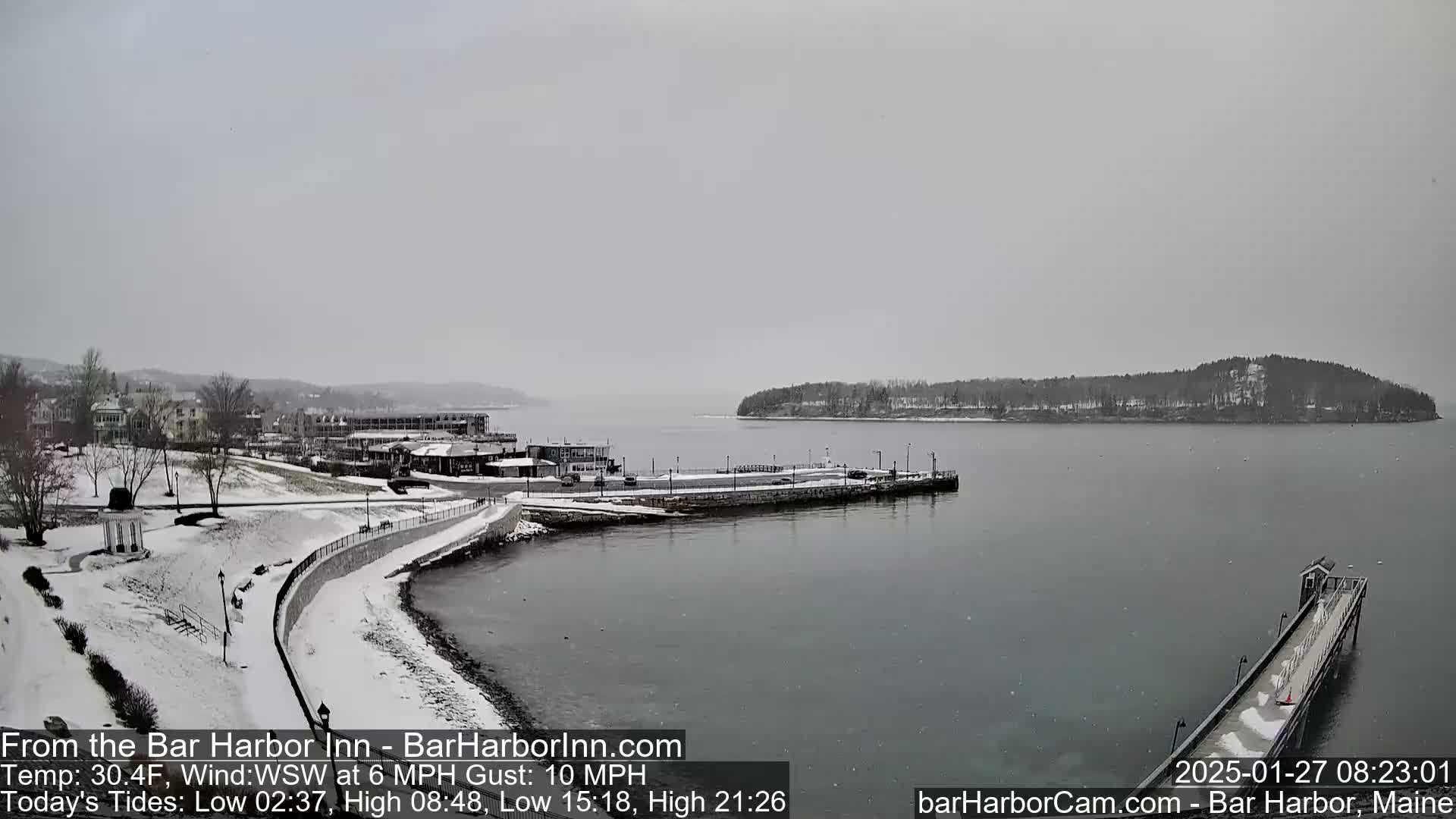 A snow-covered waterfront town and harbor are visible under an overcast sky.