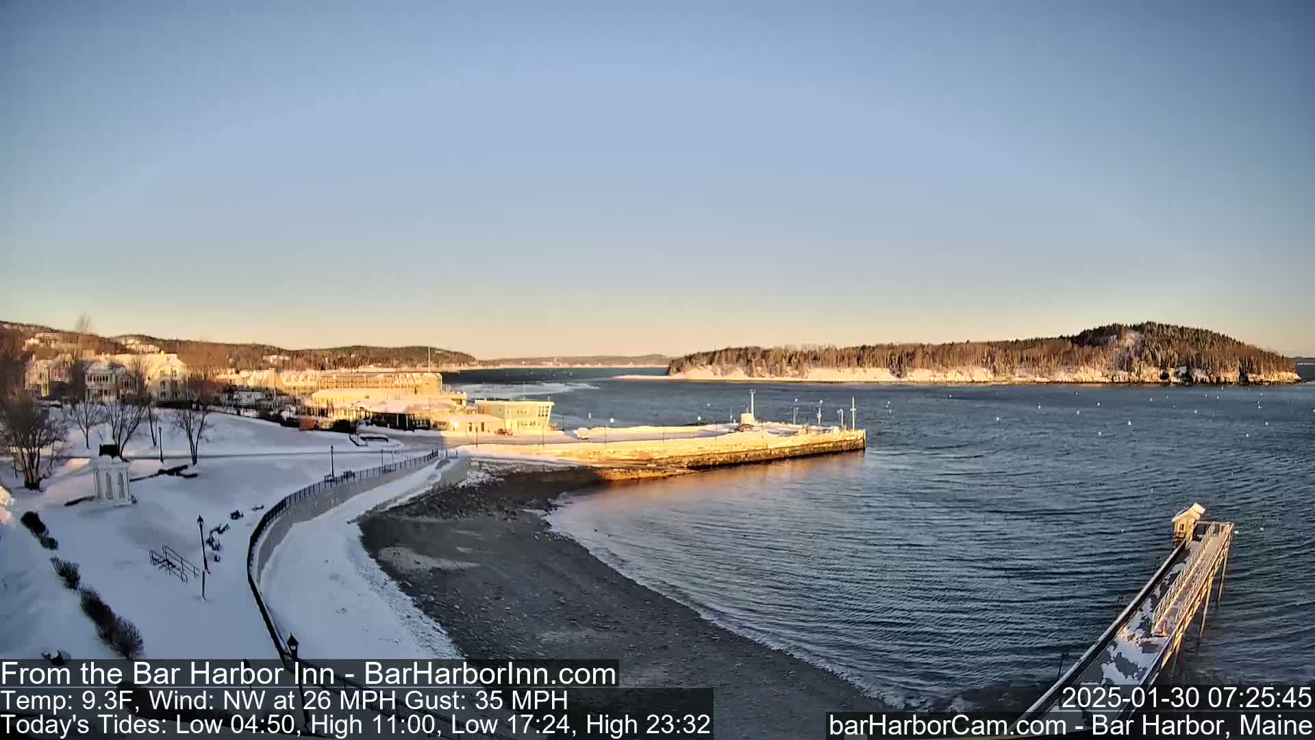 A snow-covered coastal town with a calm bay under a clear, bright sky.