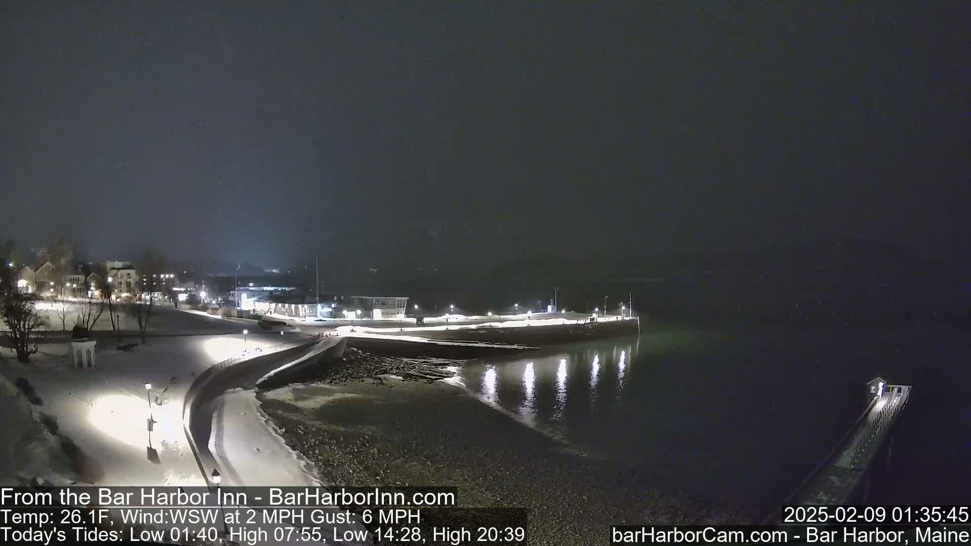 A snow-covered waterfront town at night is seen under a dark, overcast sky.