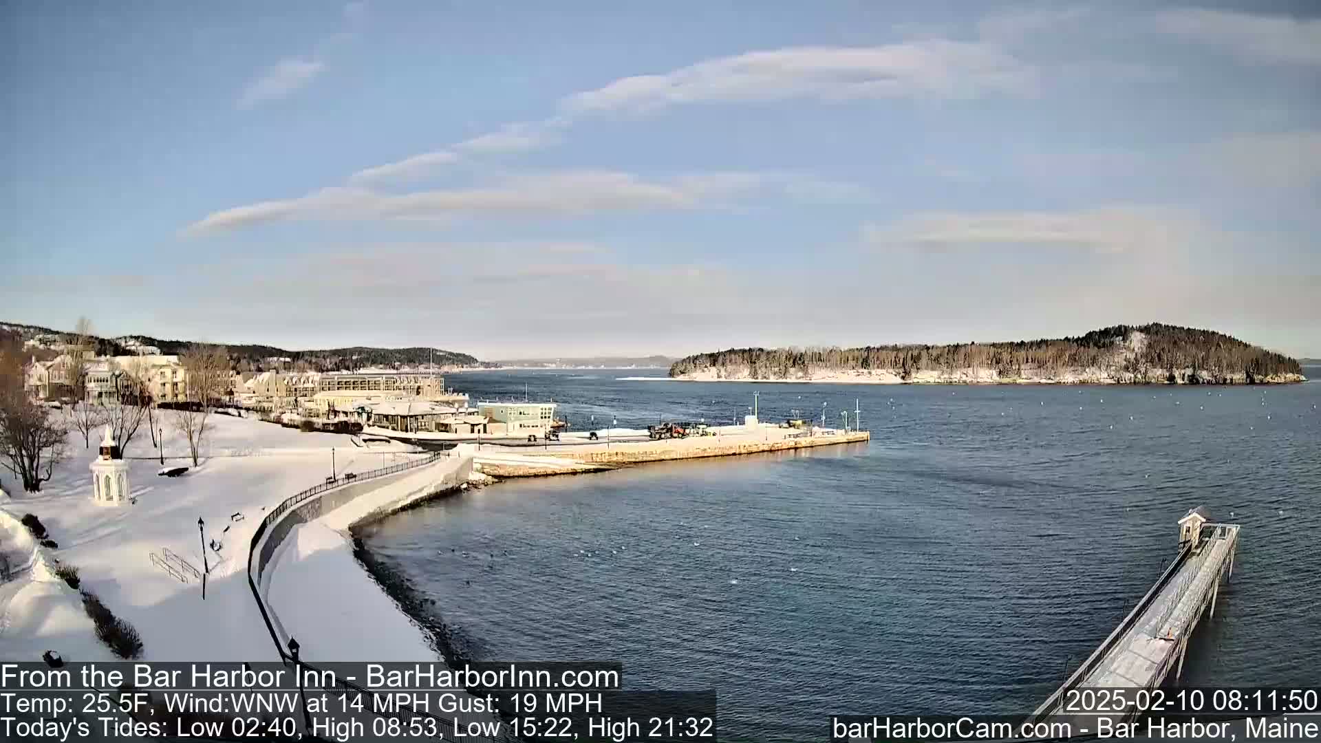 A snow-covered waterfront town with a partially frozen harbor is visible under a mostly clear sky.