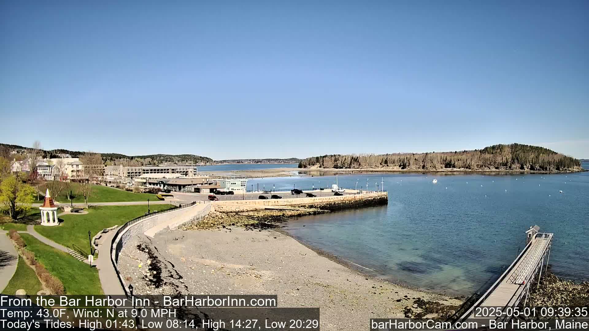 A seaside town with a calm harbor, a rocky shoreline, and a clear blue sky under sunny conditions.
