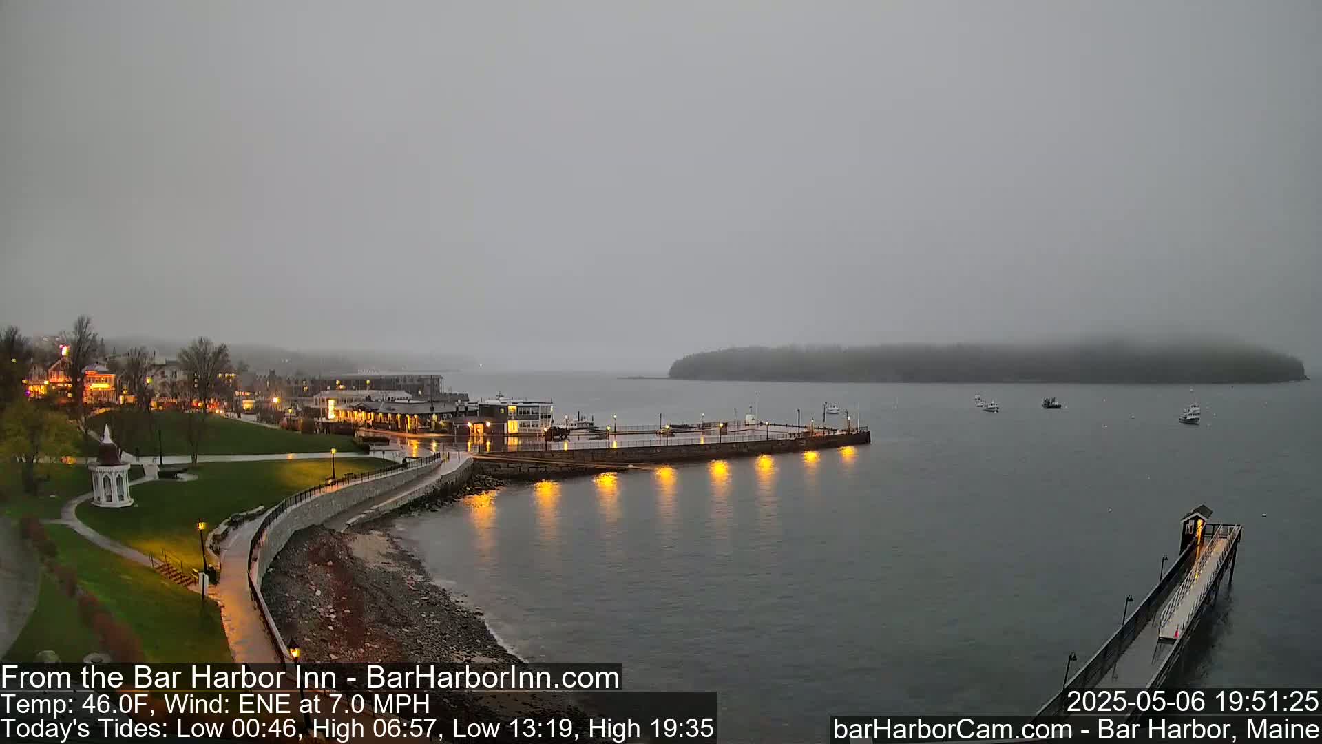 A coastal town with a long pier extending into a calm, gray body of water under an overcast sky.