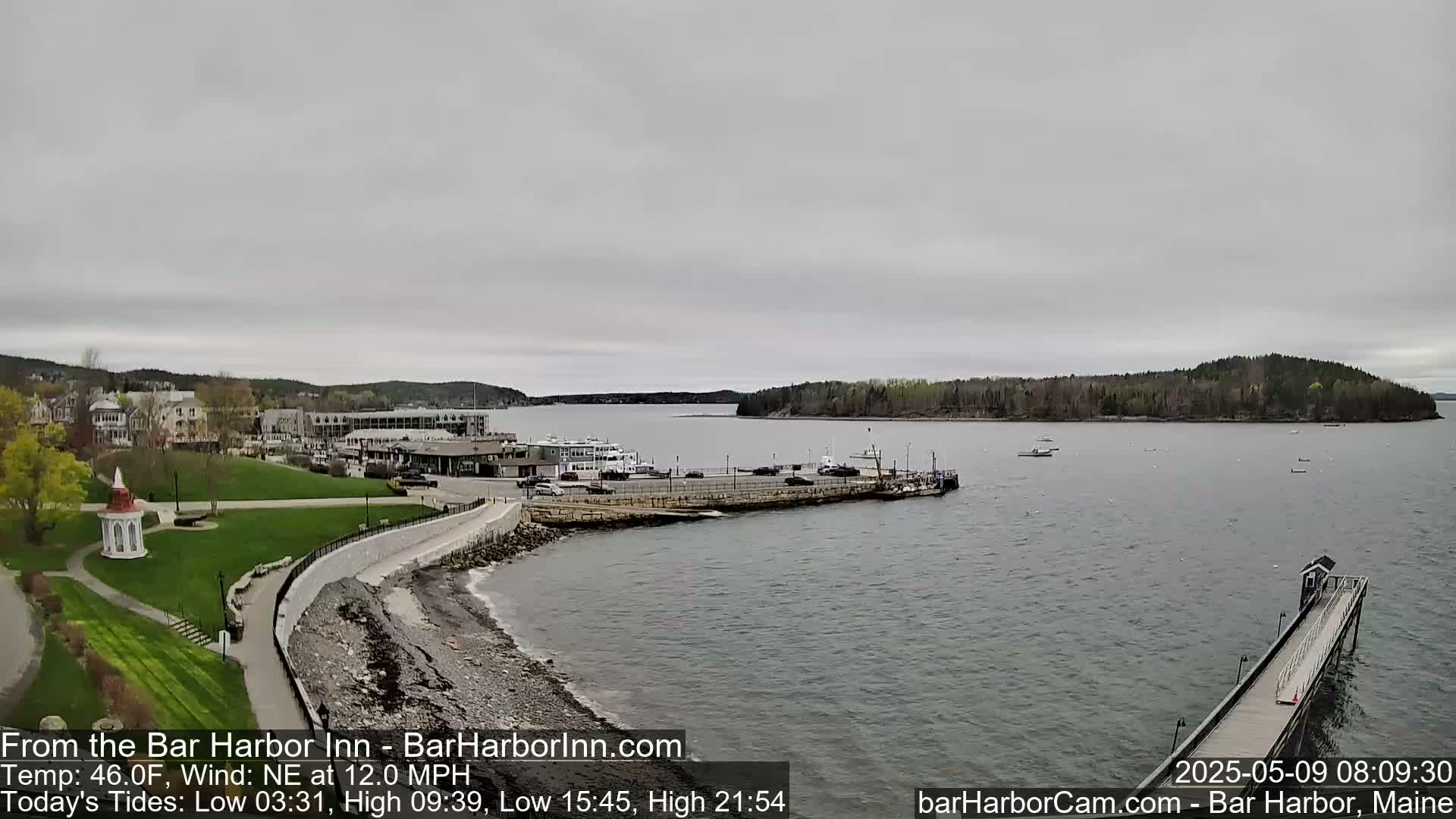 A coastal town with a harbor and several boats is visible under an overcast sky.