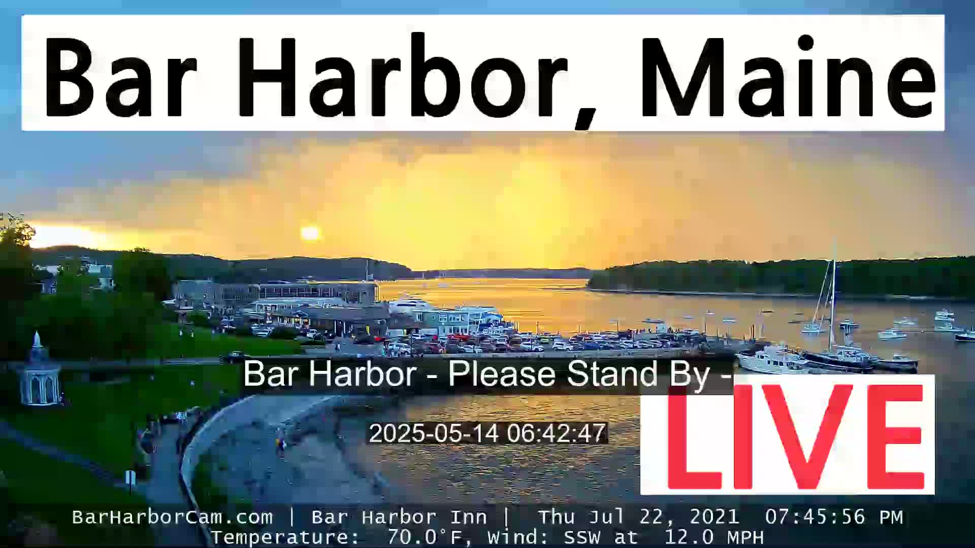 A sunset over a harbor town with many boats, showing a calm body of water under a partly cloudy, golden sky.