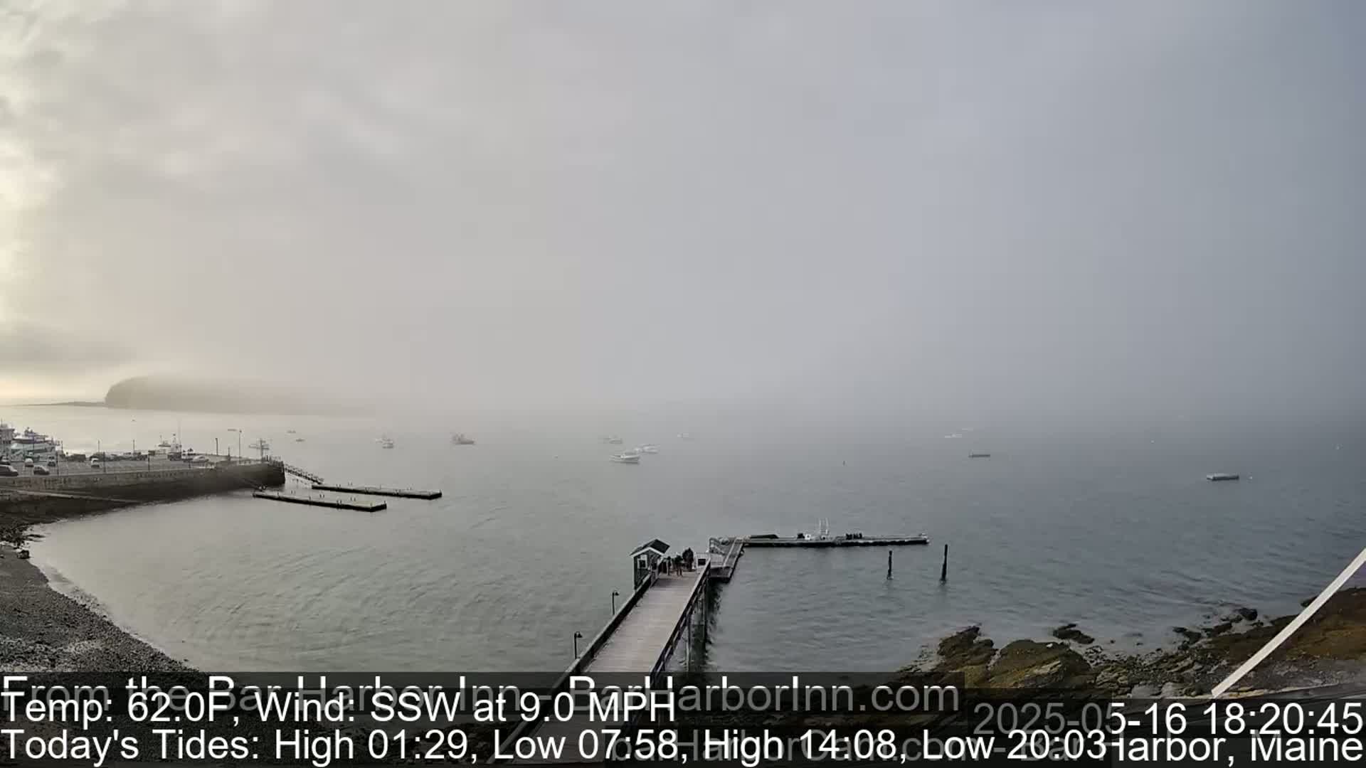A foggy harbor scene shows several boats at docks and in the water, with a small island barely visible in the distance.