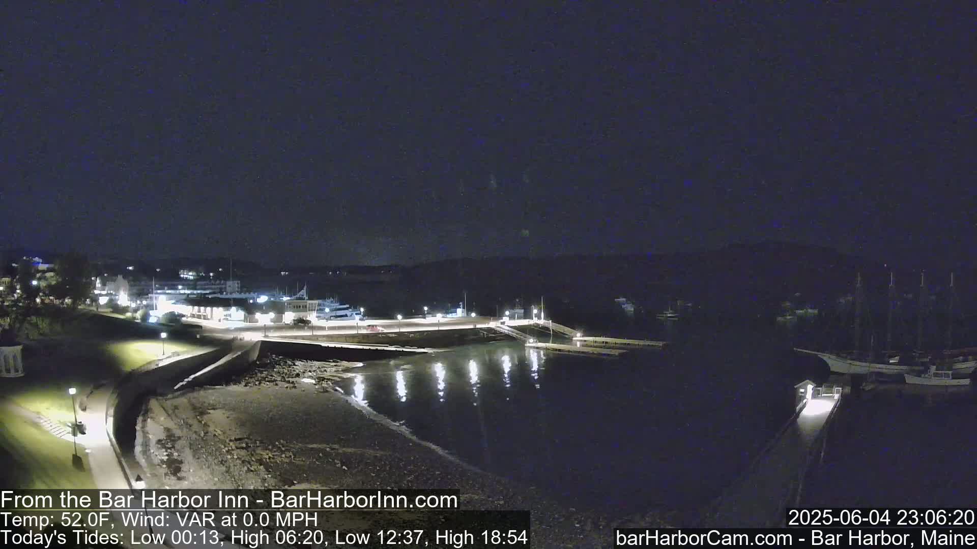 A nighttime view of a harbor, with calm water reflecting lights from buildings and docks on a clear night.
