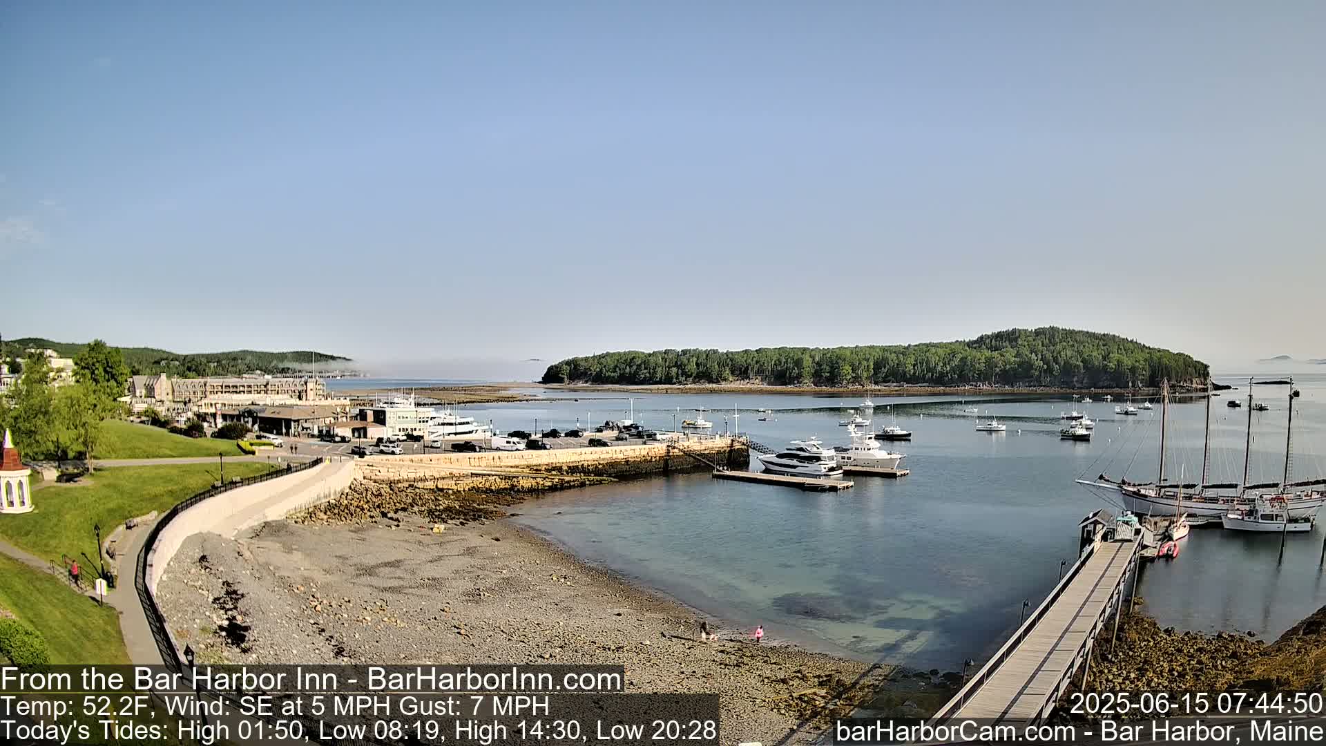 A harbor filled with boats on a partly sunny day, with a light southeast wind,  under a clear sky and a light fog in the distance.