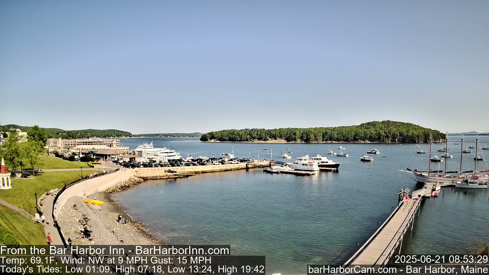 A harbor with numerous boats and a large hotel is visible on a sunny day with a northwest wind.
