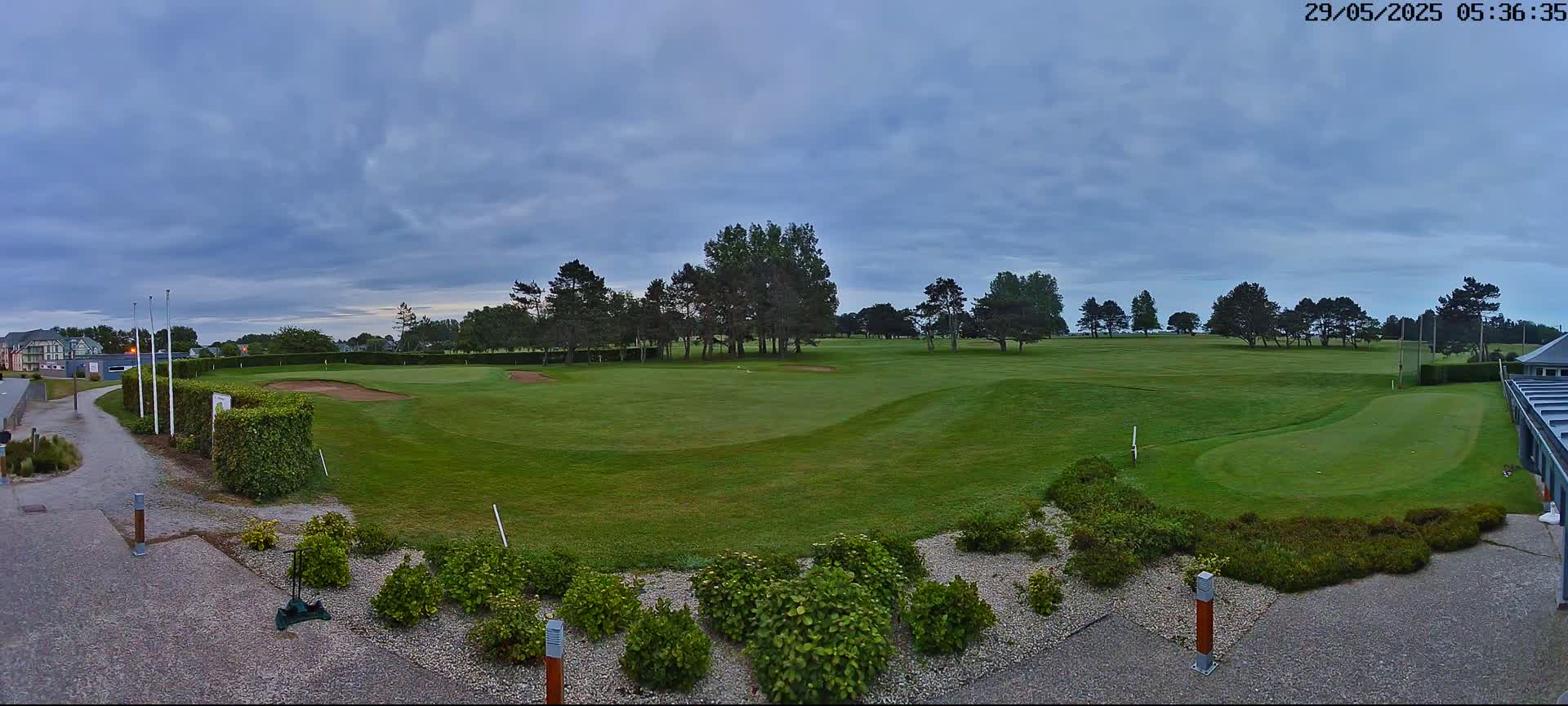 A golf course with green fairways and sand traps under a cloudy sky.