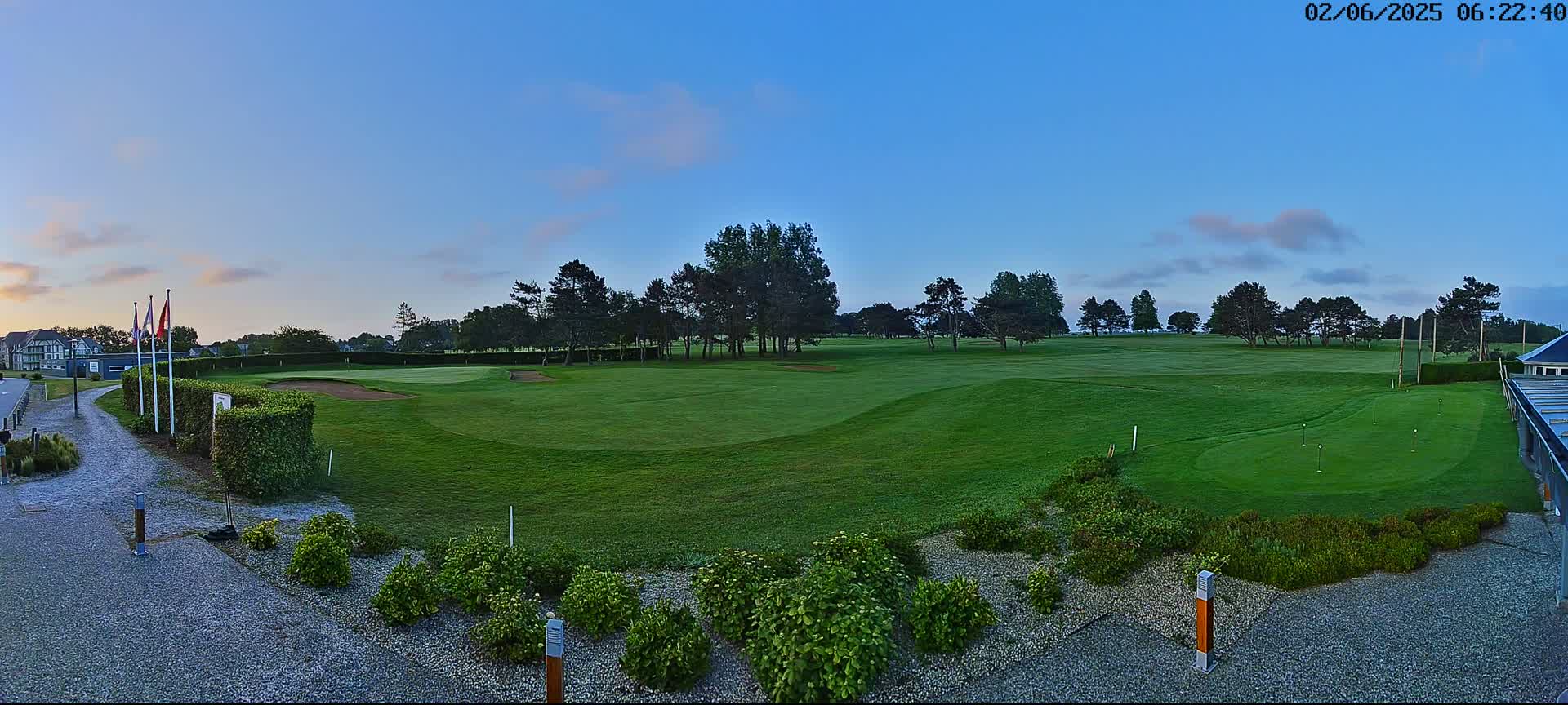 A lush green golf course stretches out under a clear, twilight sky, with a few clouds visible.