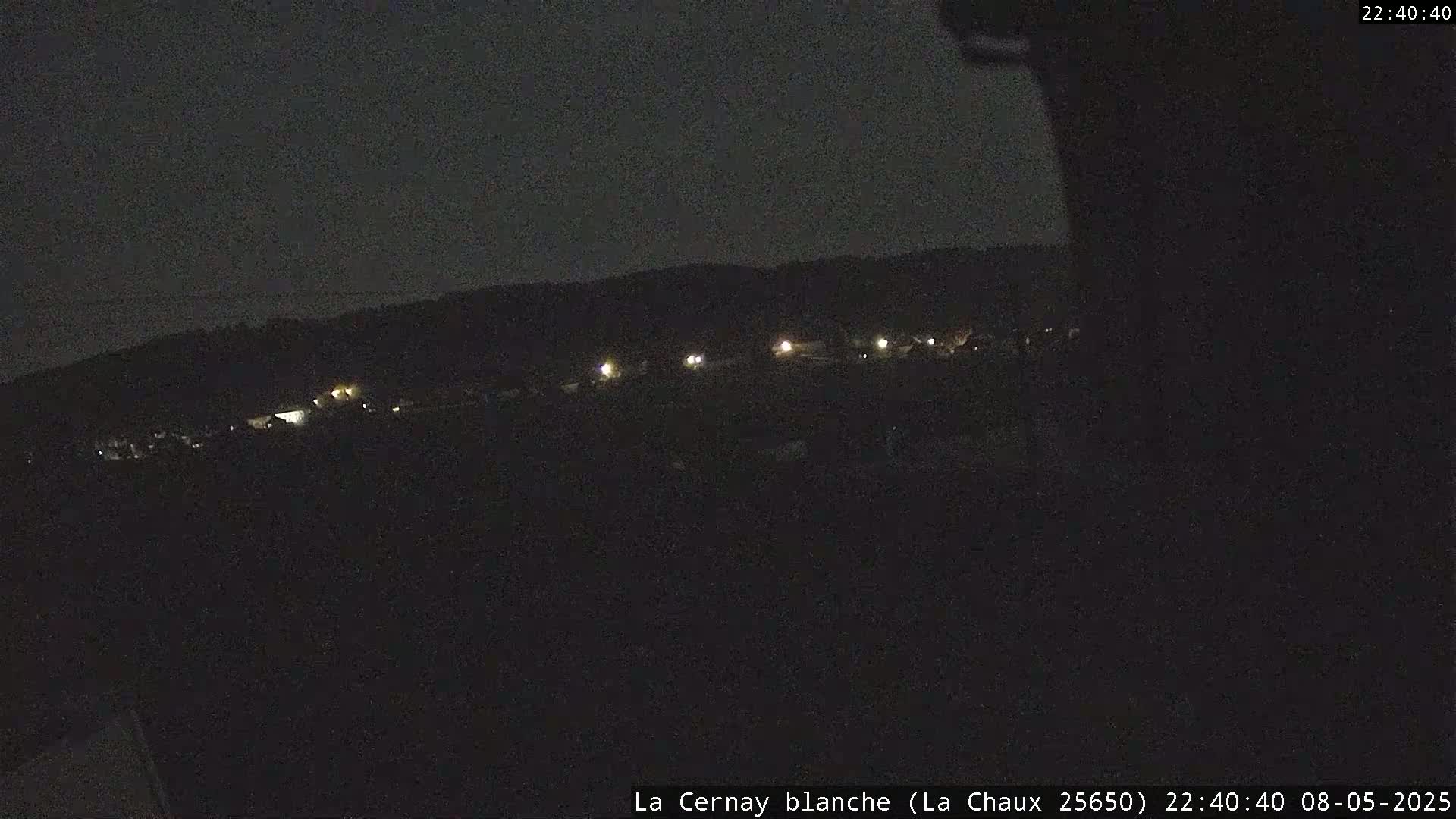 A nighttime long shot shows a dark landscape with a few distant lights.