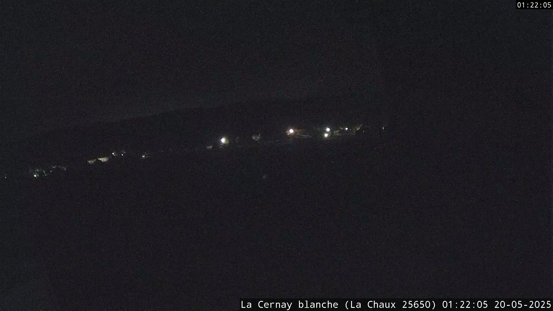 A dark, nighttime scene shows a few faint lights in the distance.