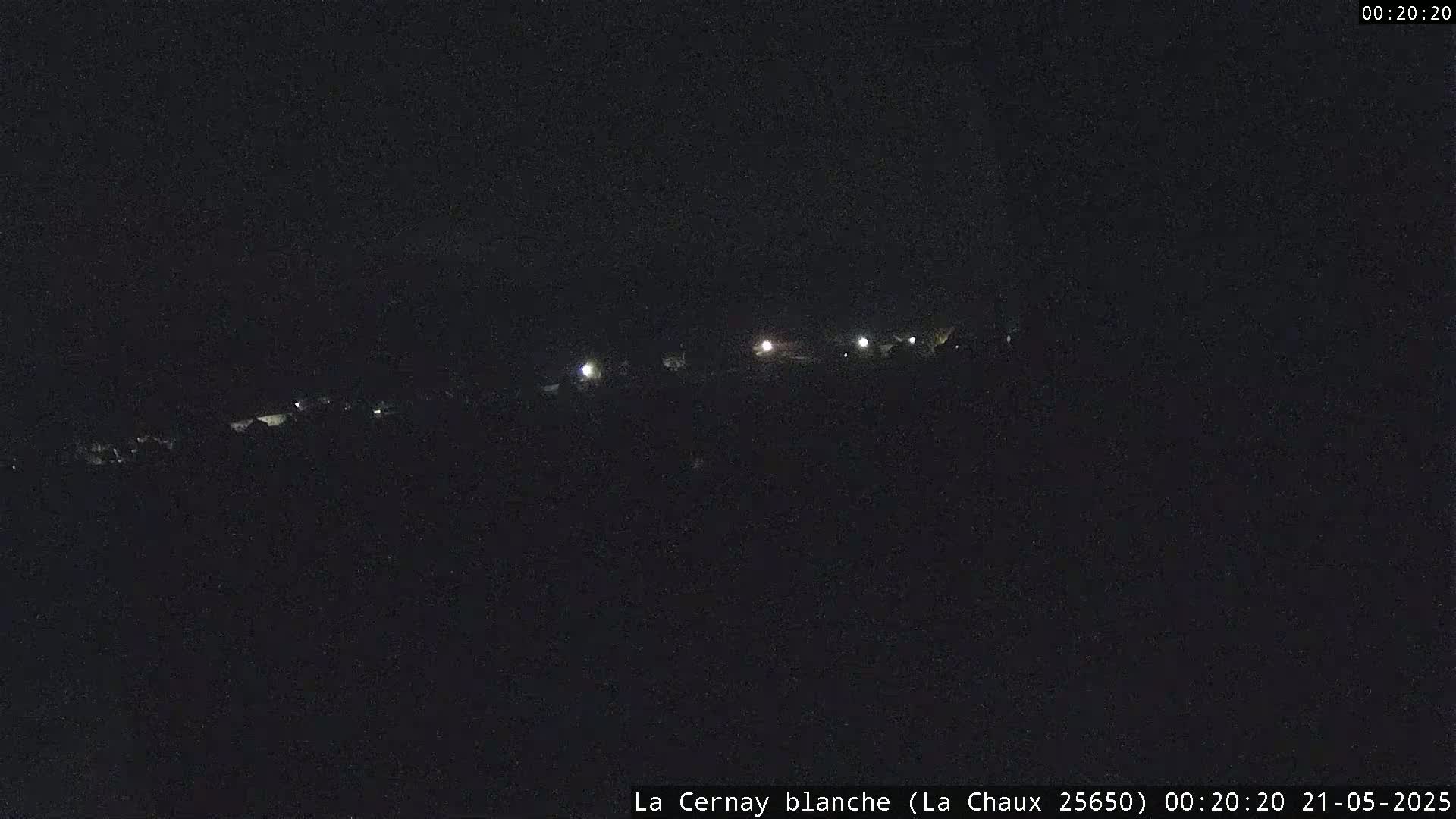 A dark, nighttime scene shows a line of faint lights in the distance.