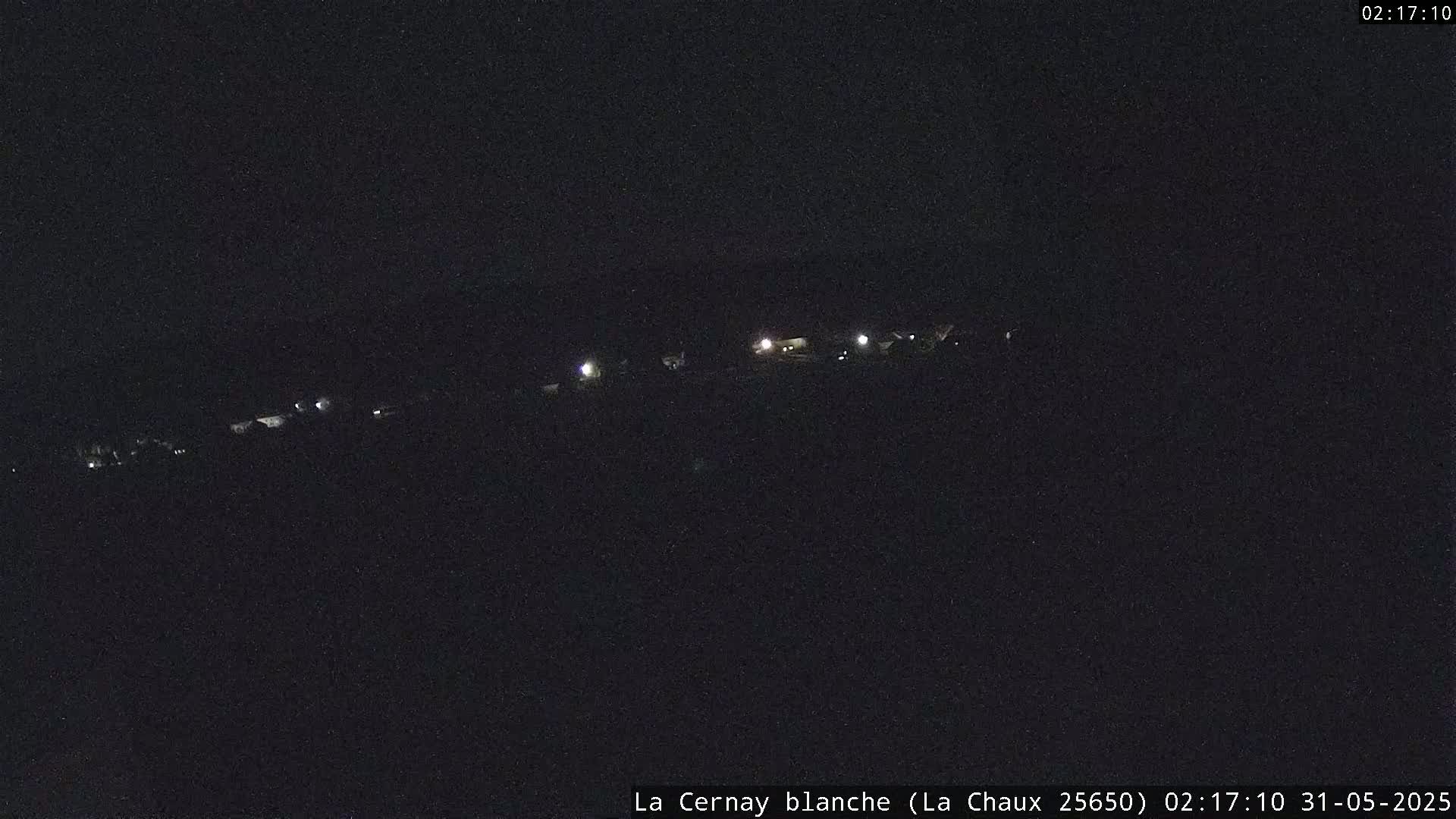 A nighttime, long-range view of a sparsely lit area, possibly a small town or village.