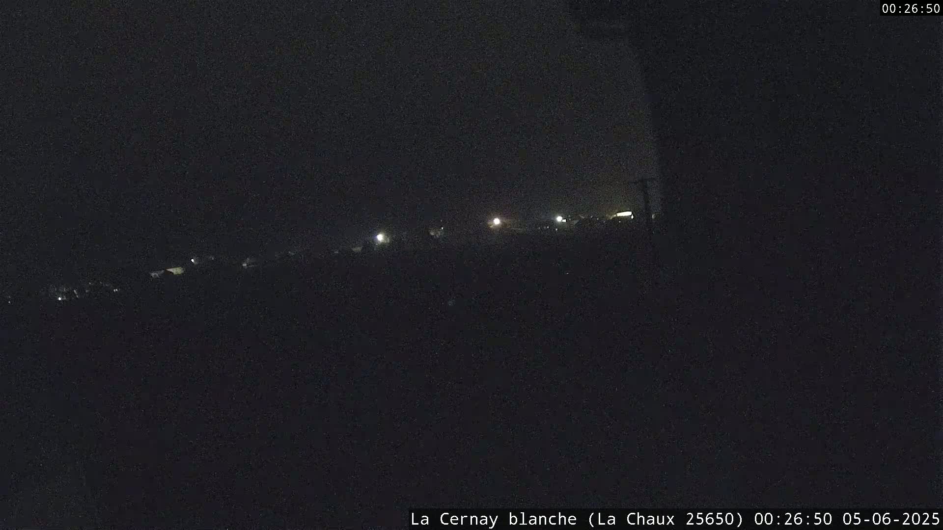 A dark, nighttime scene shows a few distant lights in the far background.