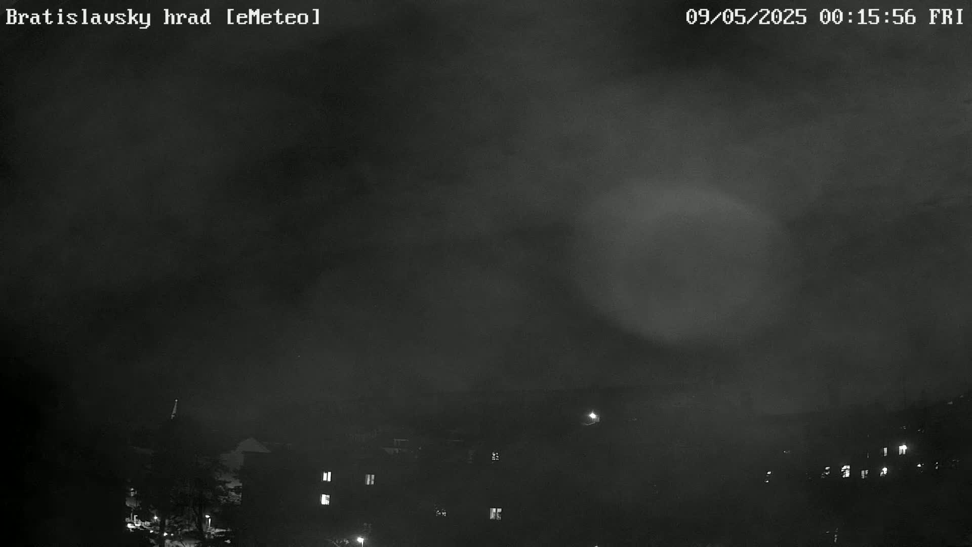 A nighttime, cloudy view of a town with dimly lit buildings.